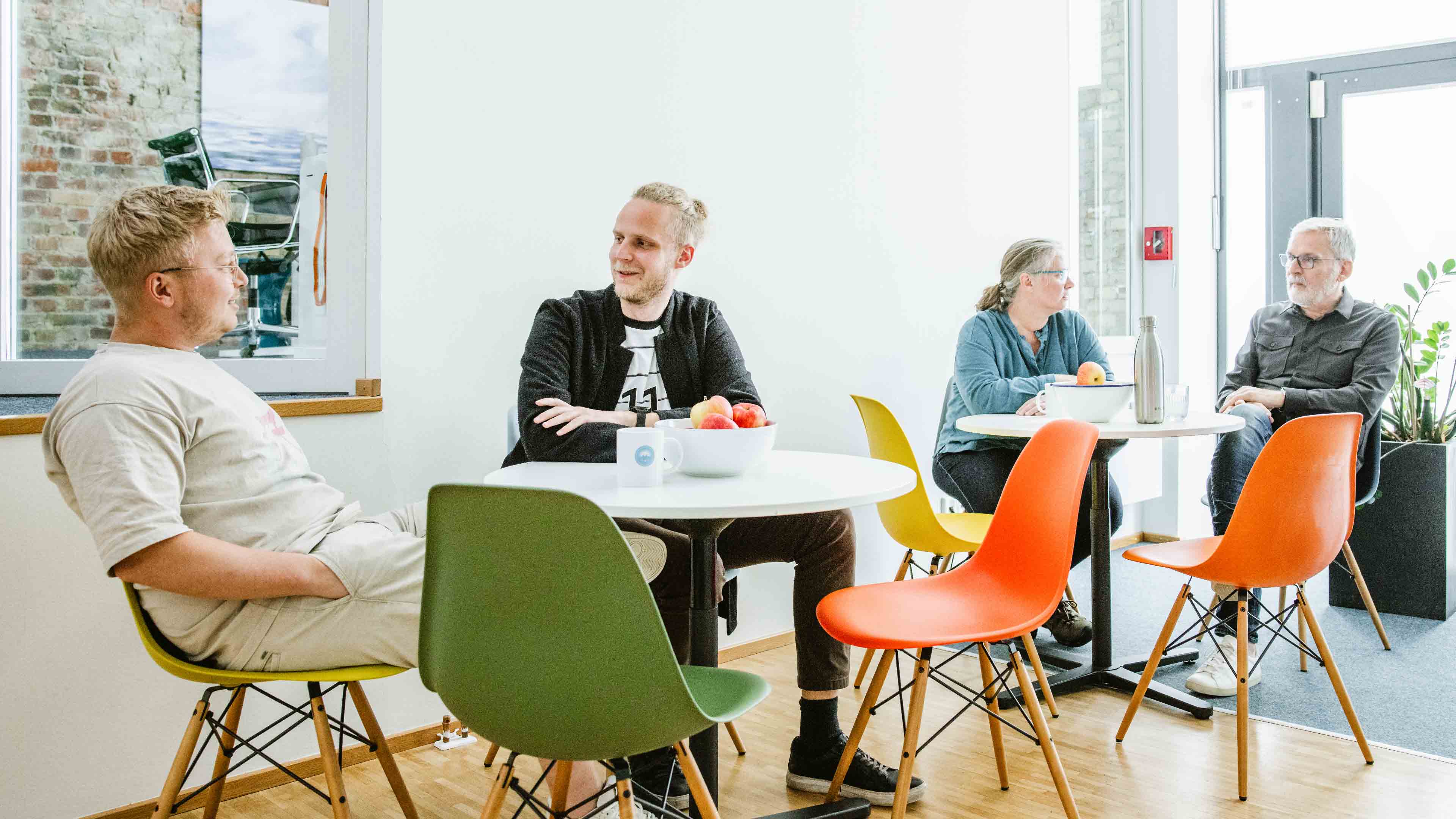 h2_werIst_slider_03.jpg Vier Angestellte von Hochzwei an zwei Esstischen in ihrer Mittagspause.