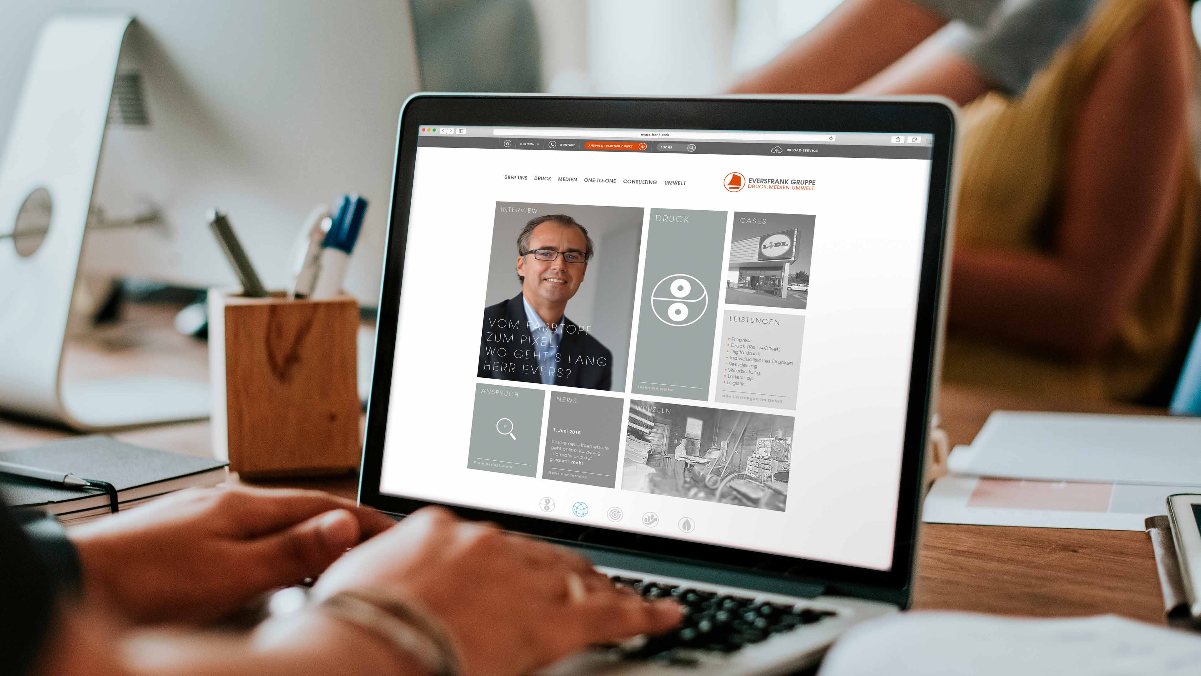 hochzwei_evdr_slider_01.jpg Hände an Laptop, das graue Teaserkacheln auf Website der Eversfrank Gruppe zeigt