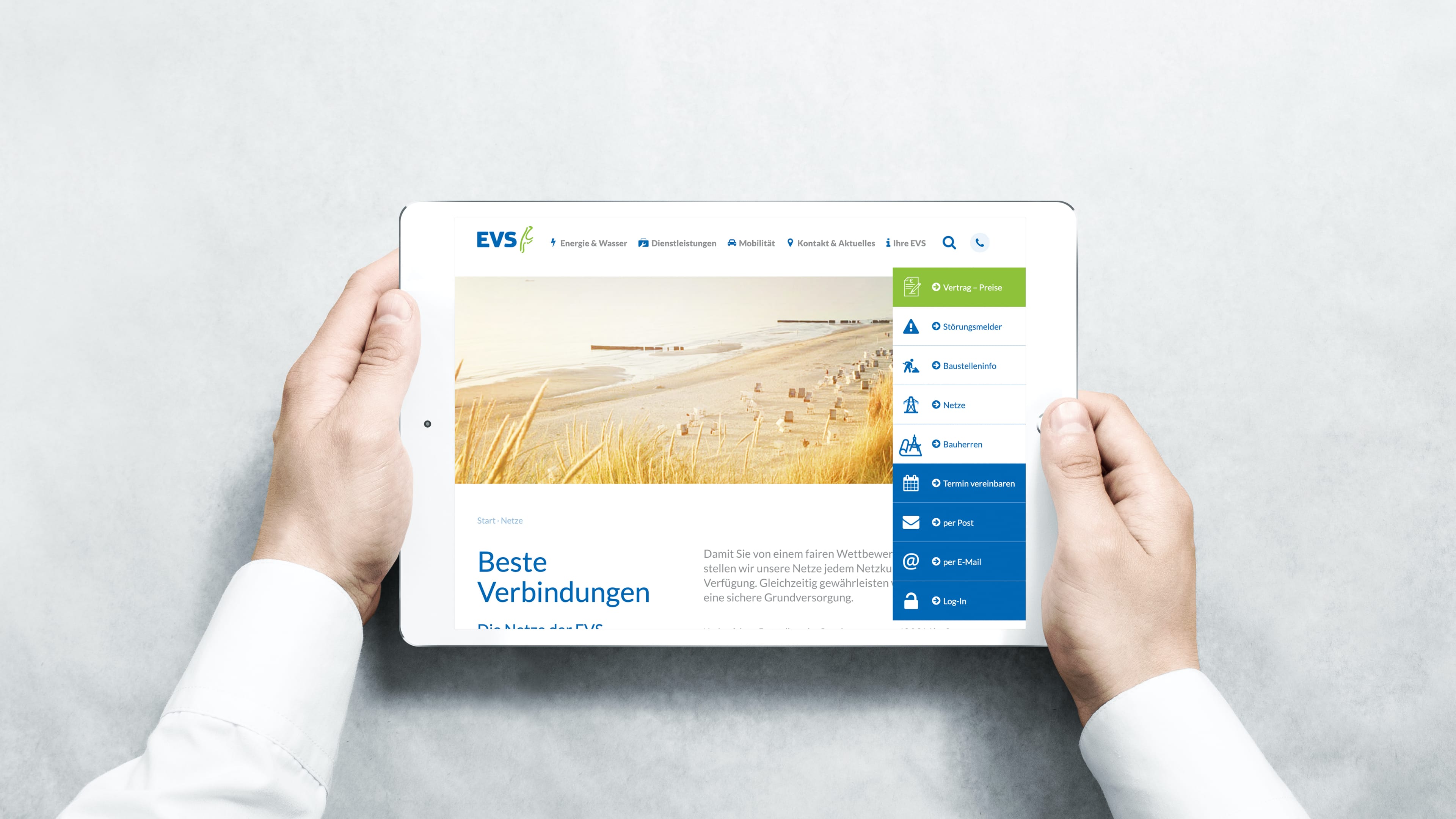 hochzwei_evs_slider_01.jpg Zwei Hände halten weißes Tablet, das Website und Strandbild zeigen