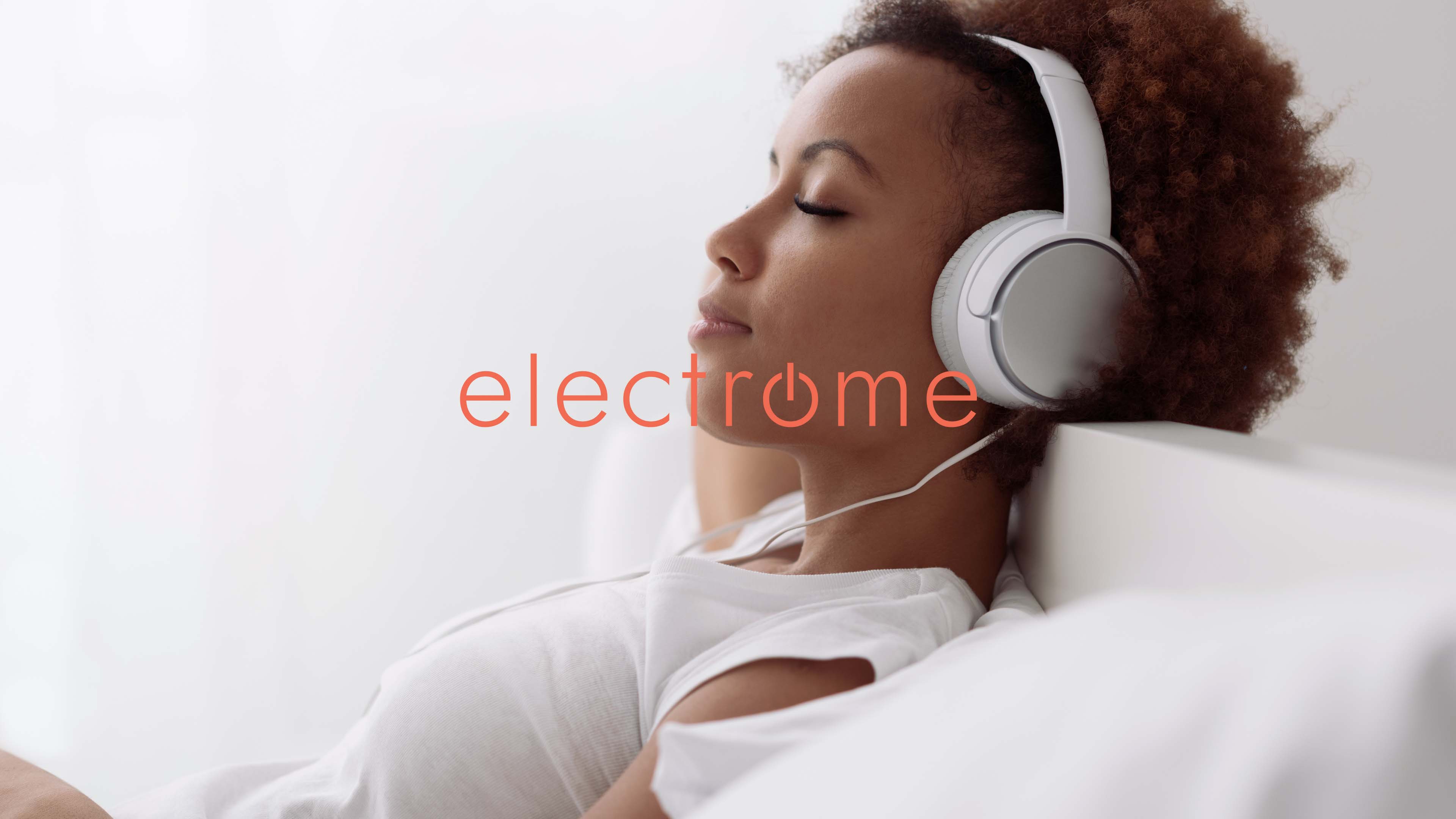 Eine Frau sitzt mit Kopfhörern auf dem Sofa