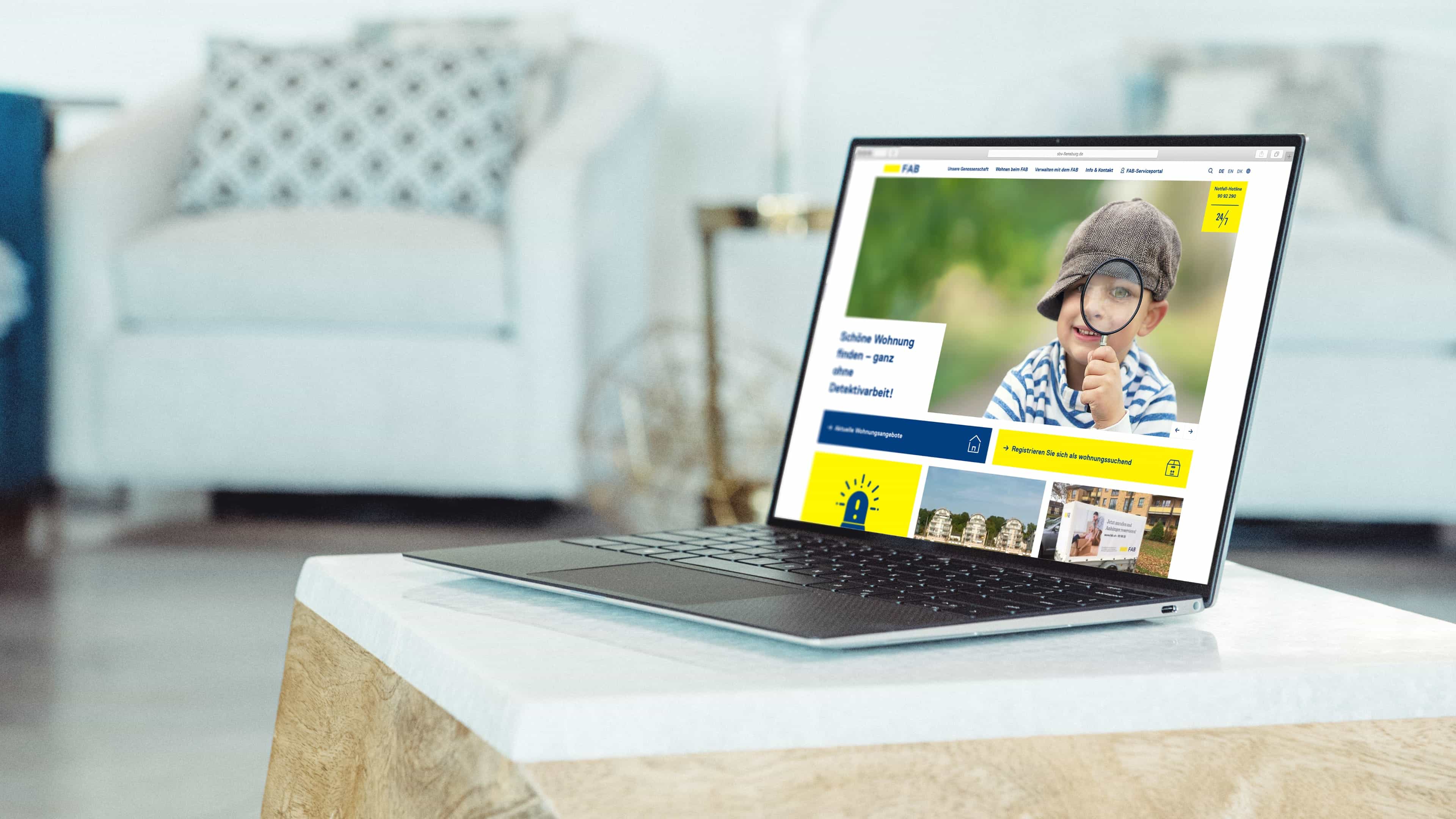 Laptop auf Couchtisch zeigt FAB-Website und Jungen mit Lupe