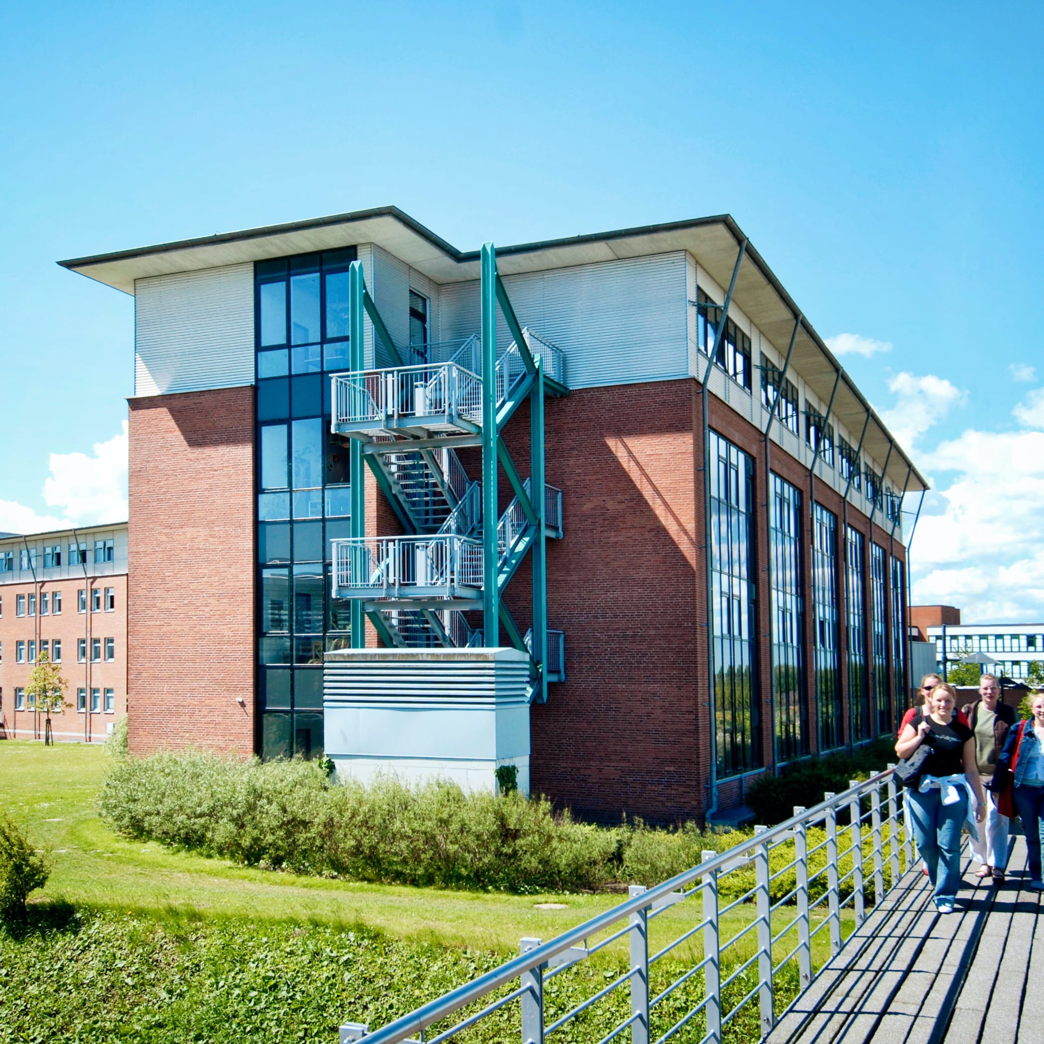 hochzwei_fhfl_teaser_04.jpg Vierstöckiges Klinkergebäude und Studenten