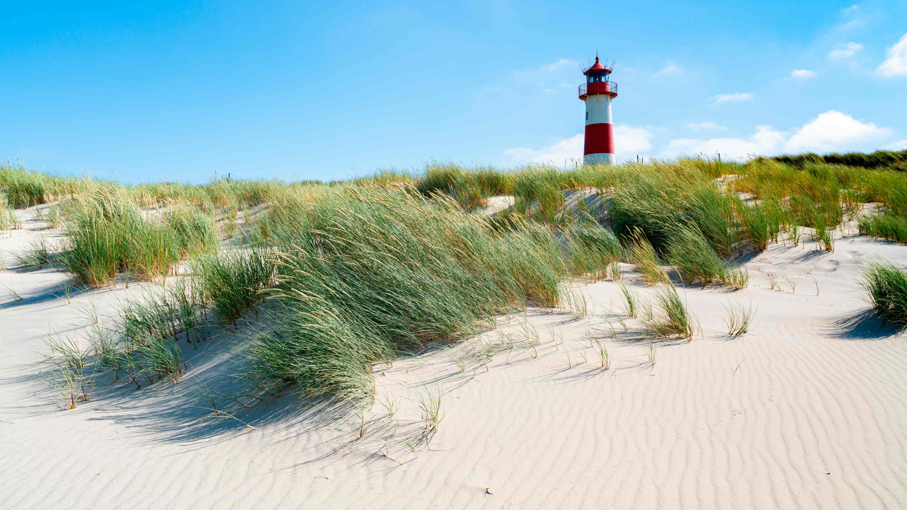 hochzwei_feano_slider_02.jpg Rot-weißer Leuchtturm und Dünensand