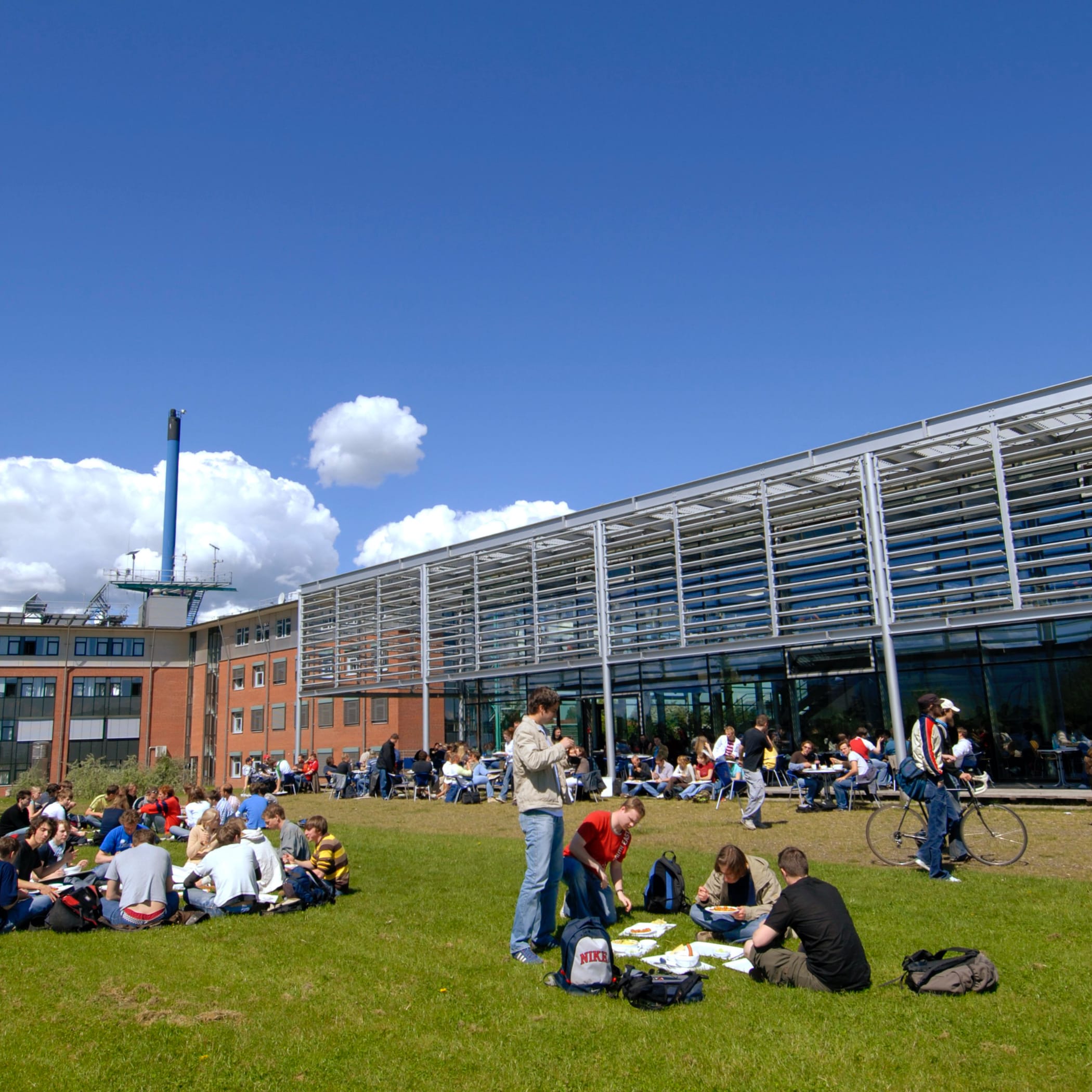 hochzwei_fhfl_teaser_06.jpg Studenten sitzen in Gruppen vor Gebäude