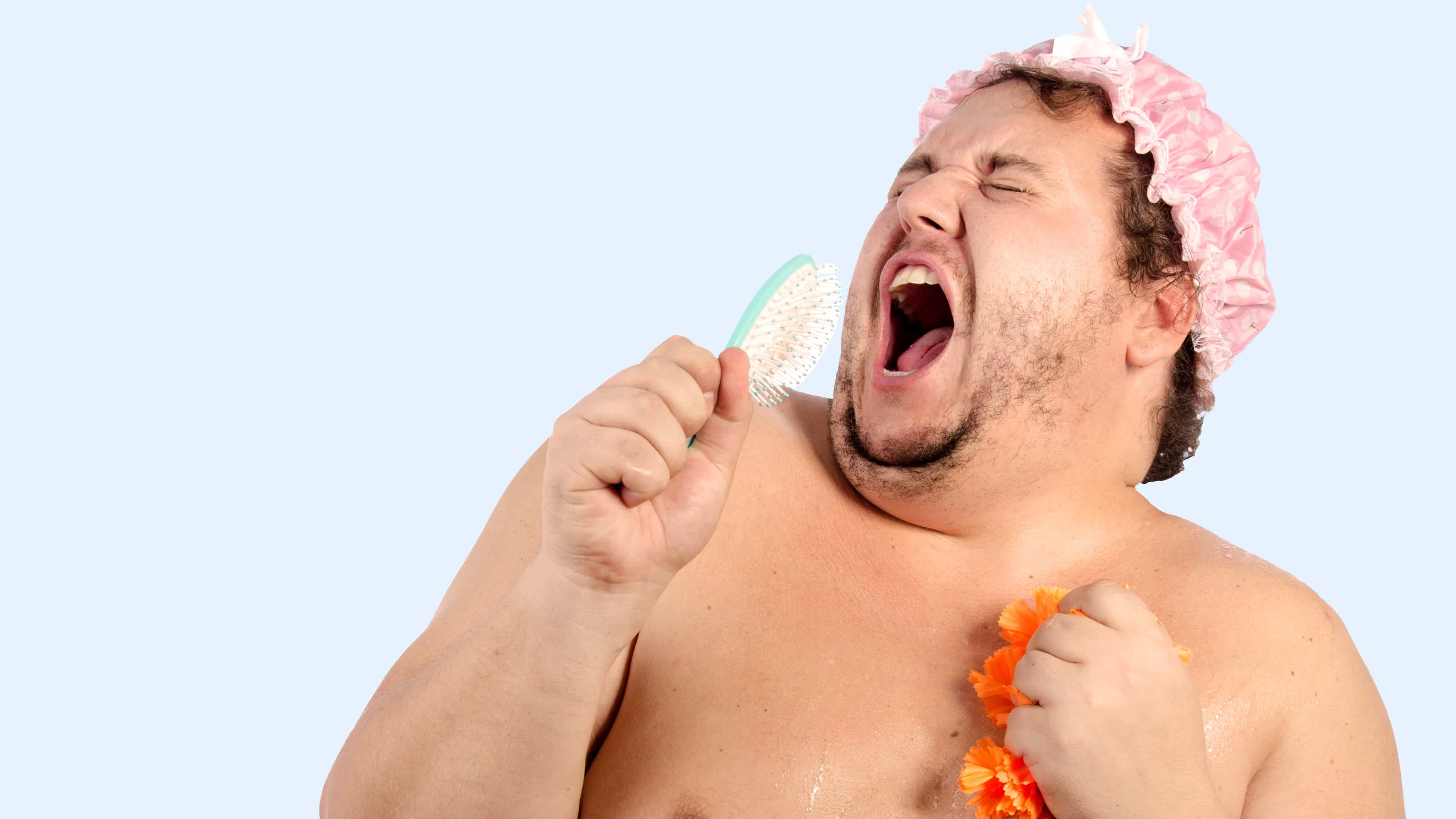 Ein Mann mit Duschhaube singt in die Bürste