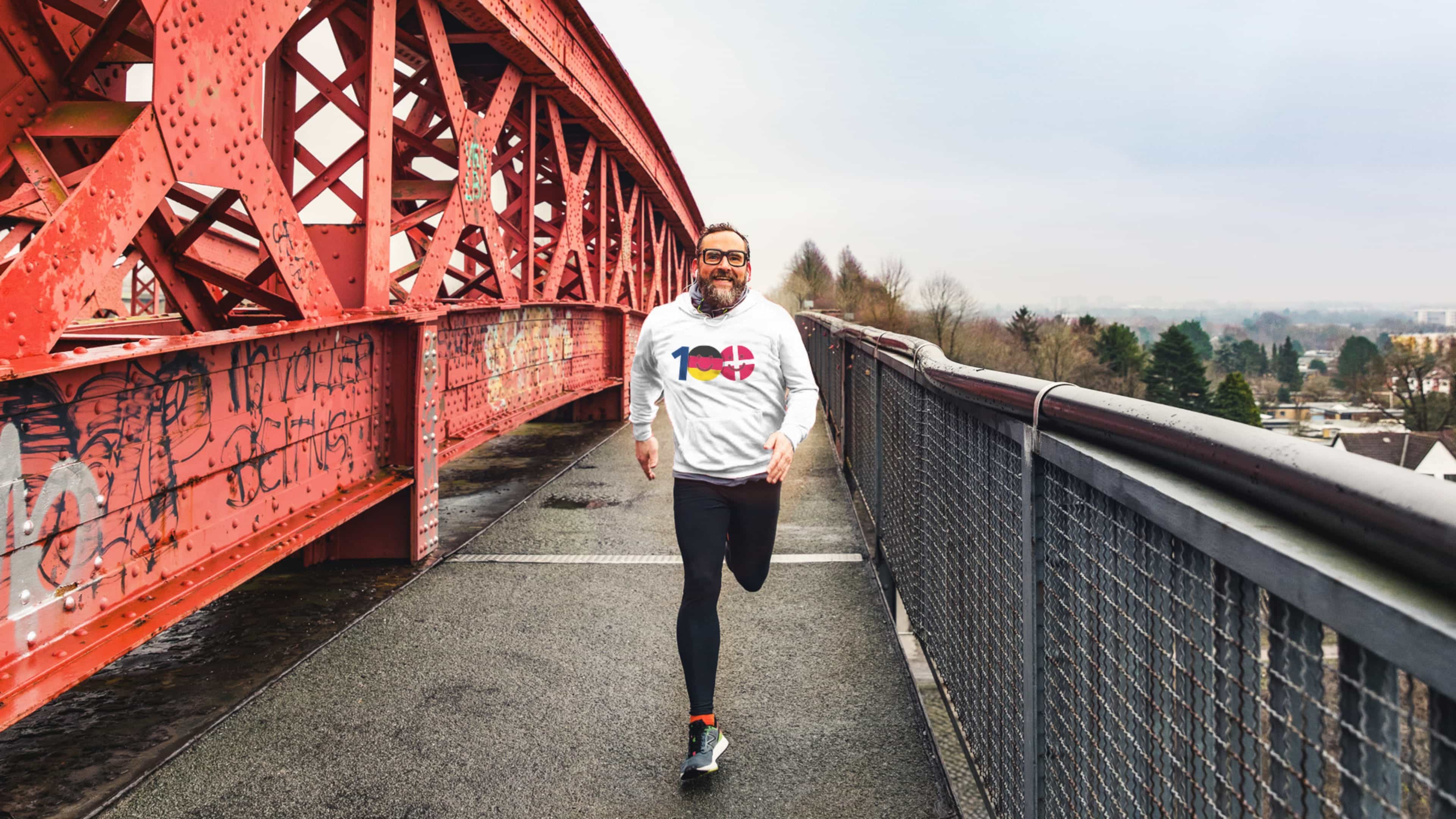 Ein Mann joggt über eine rote Brücke