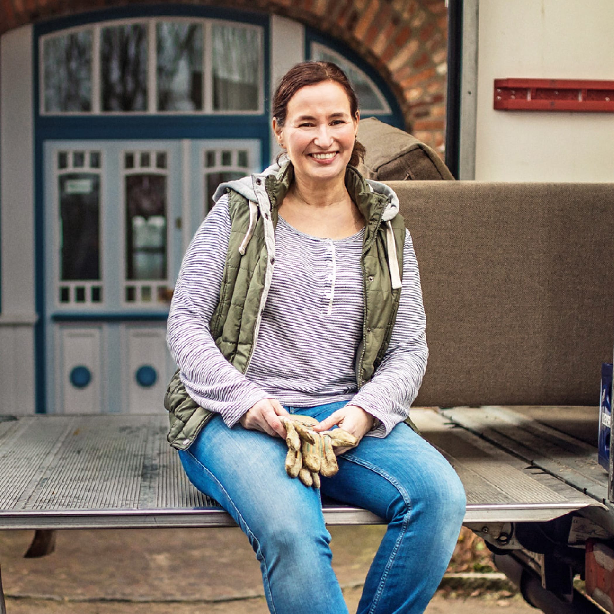 Eine brünette Frau sitzt auf einem Kofferraum