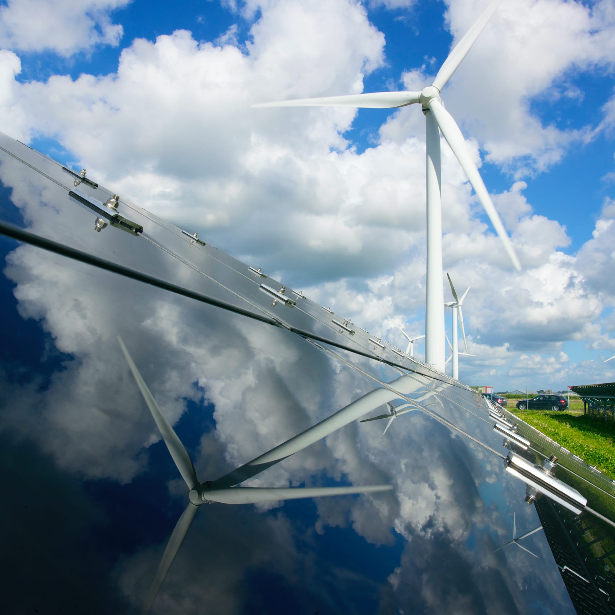 hochzwei_gp_james_teaser_01.jpg Ein Windrad spiegelt sich in der glänzendes Oberfläche einer Solarplatte