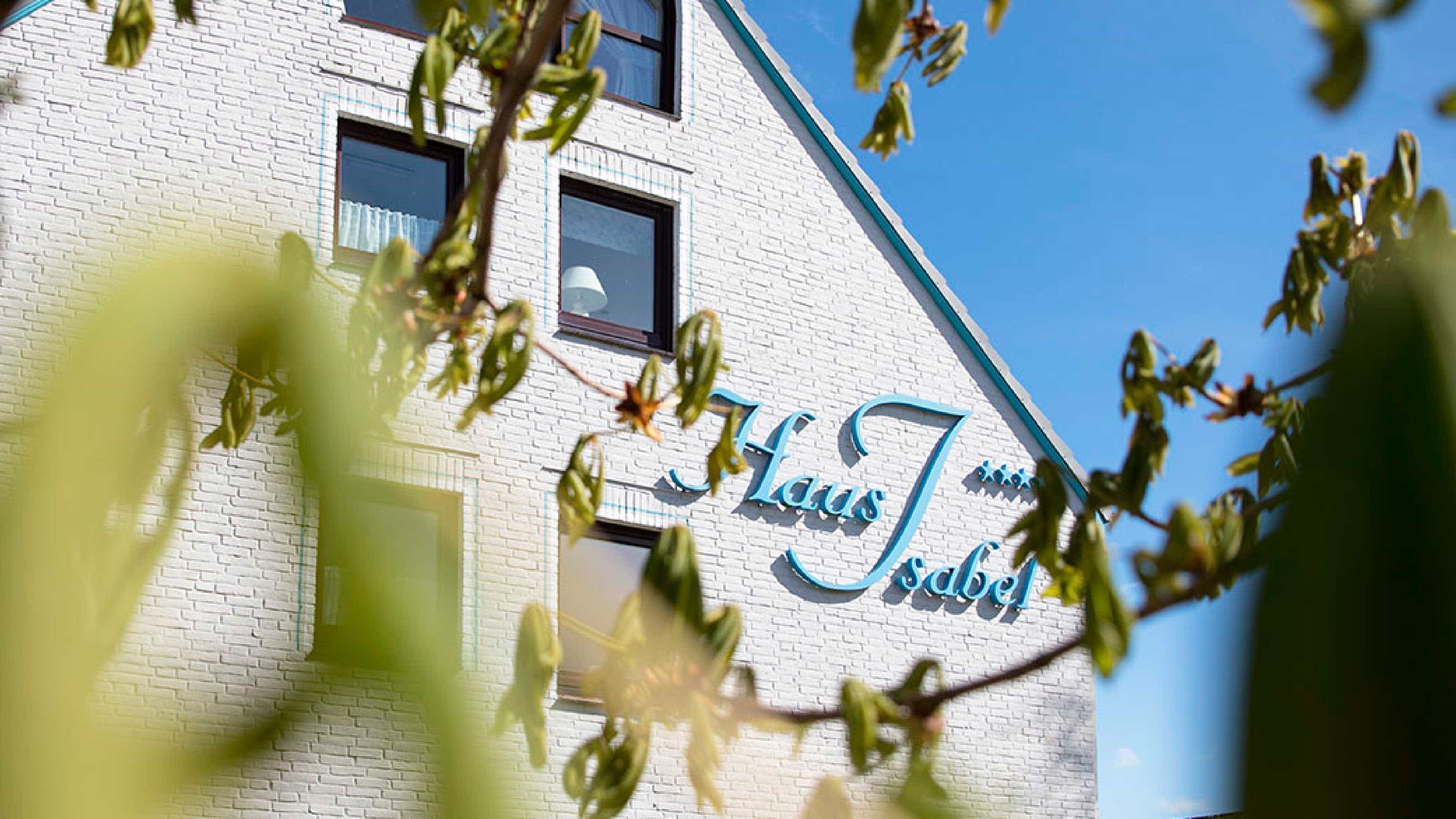 Weißes Backsteinhaus mit blauer Schrift dran