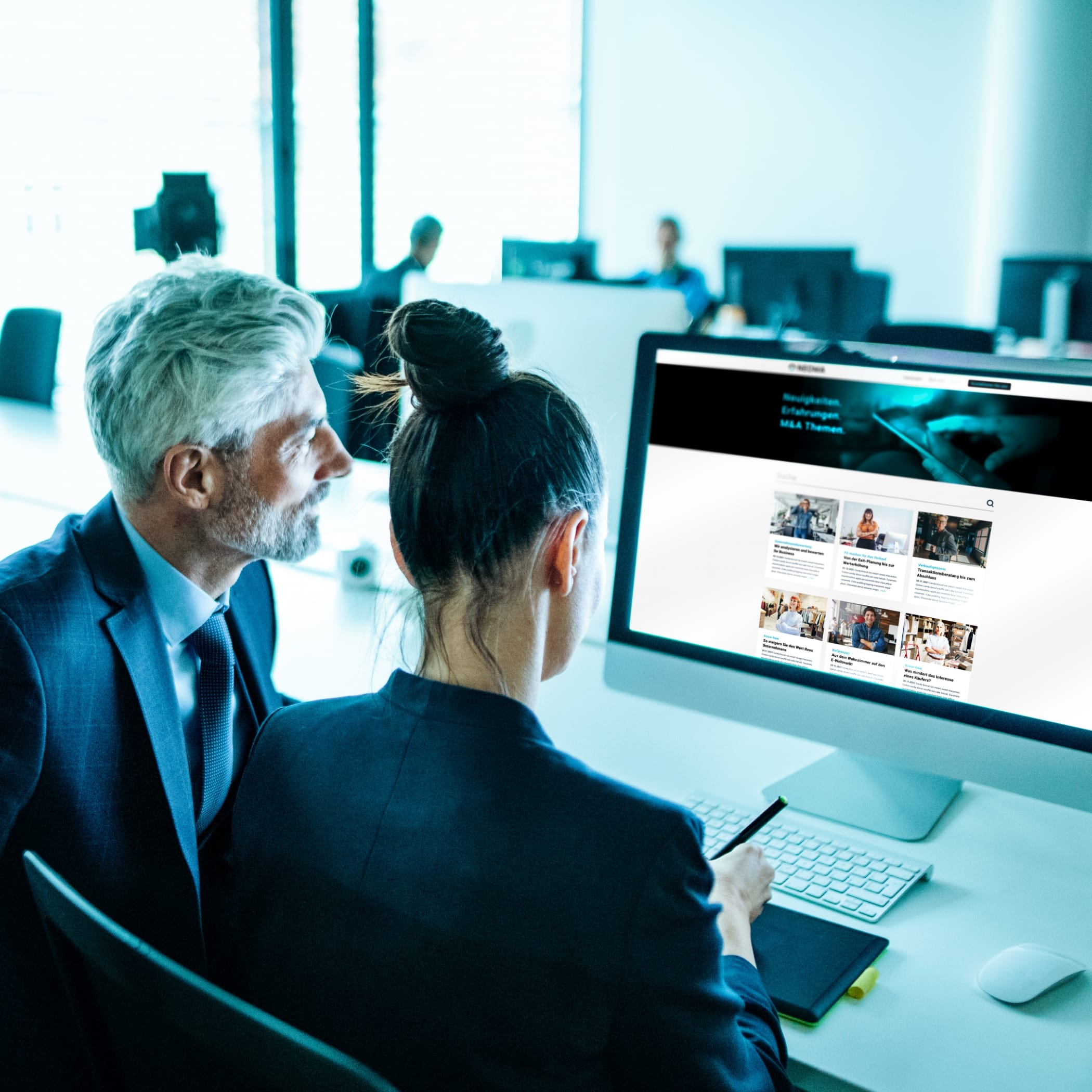 hochzwei_neoma_teaser_01.jpg Ein Mann und eine Frau in Anzügen sitzen vor einem Computer und machen sich Notizen