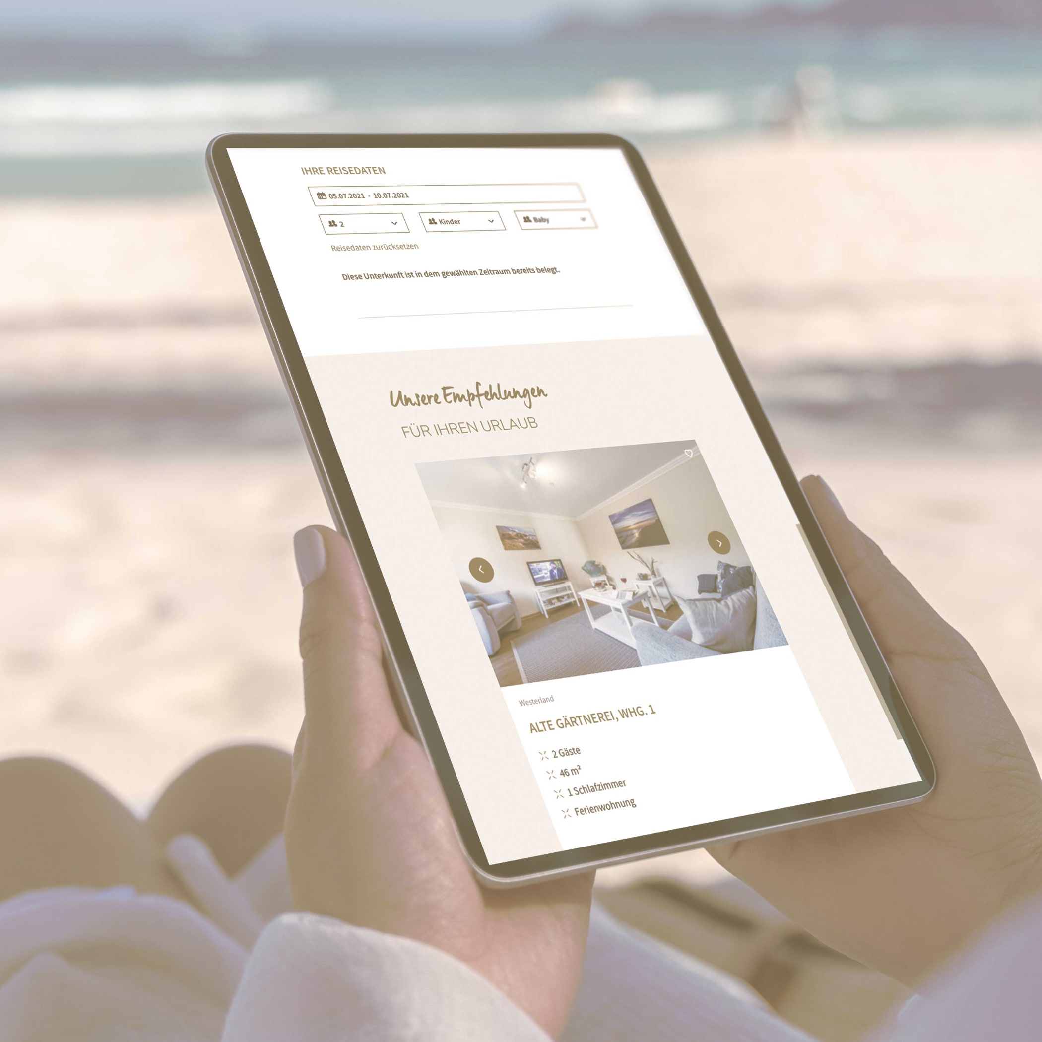 Eine Person sitzt am Strand und hält ein Ipad in der Hand