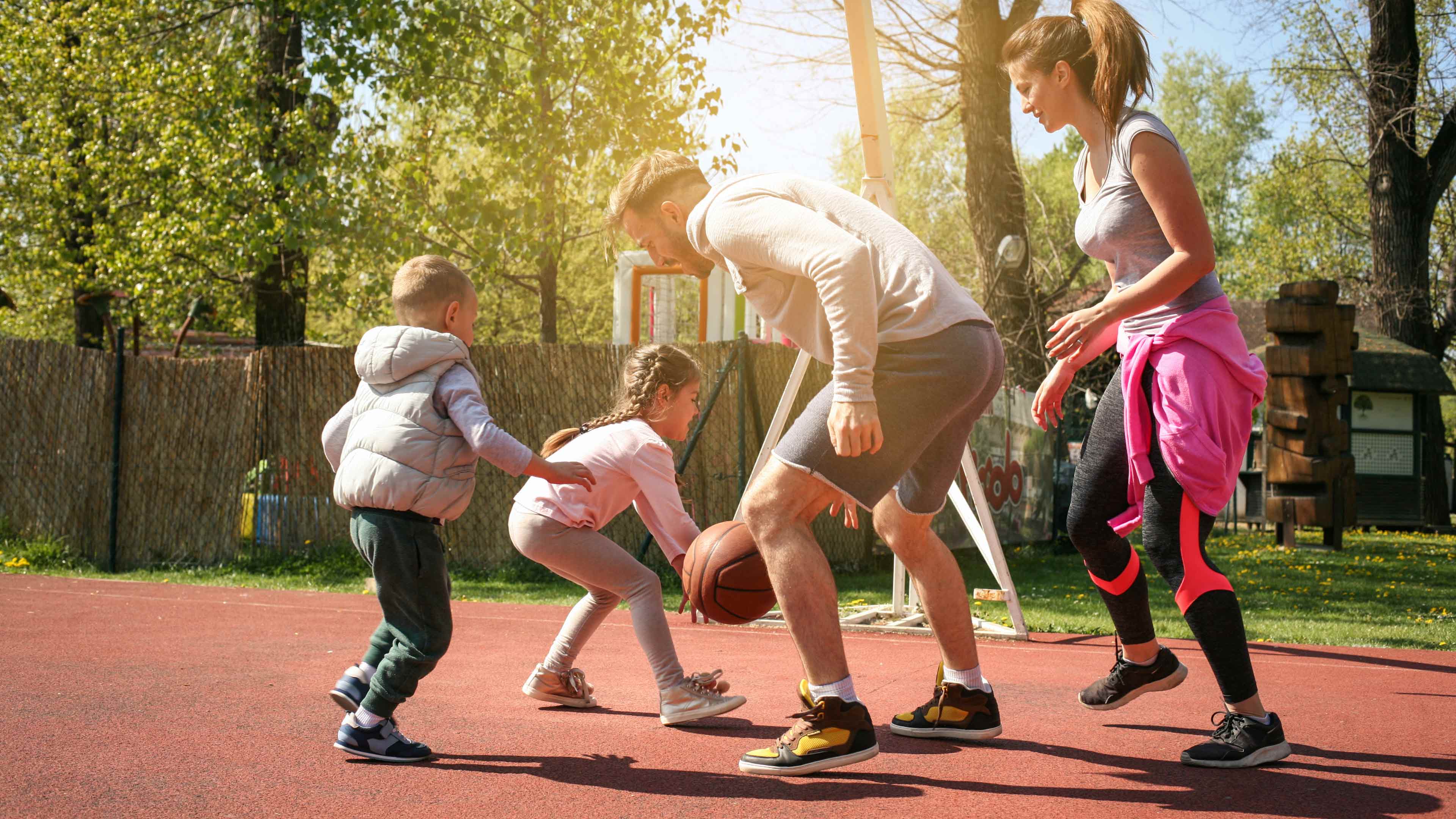 Mutter und Vater spielen Basketball mit ihren Kindern