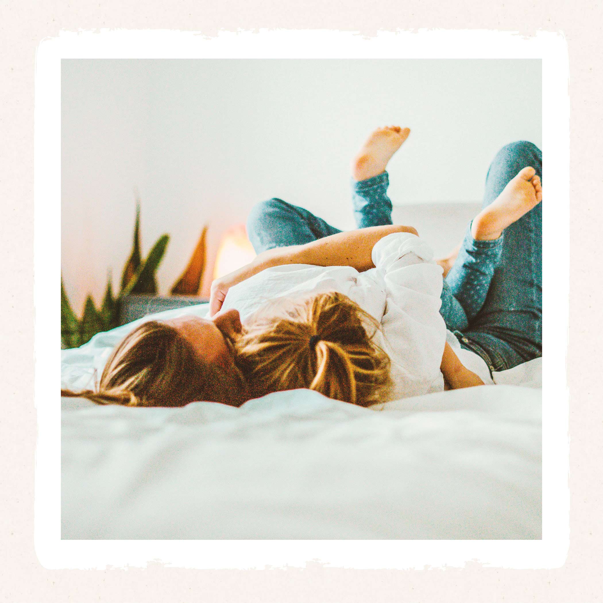 Frau und Kind liegen auf einem weißen Bett