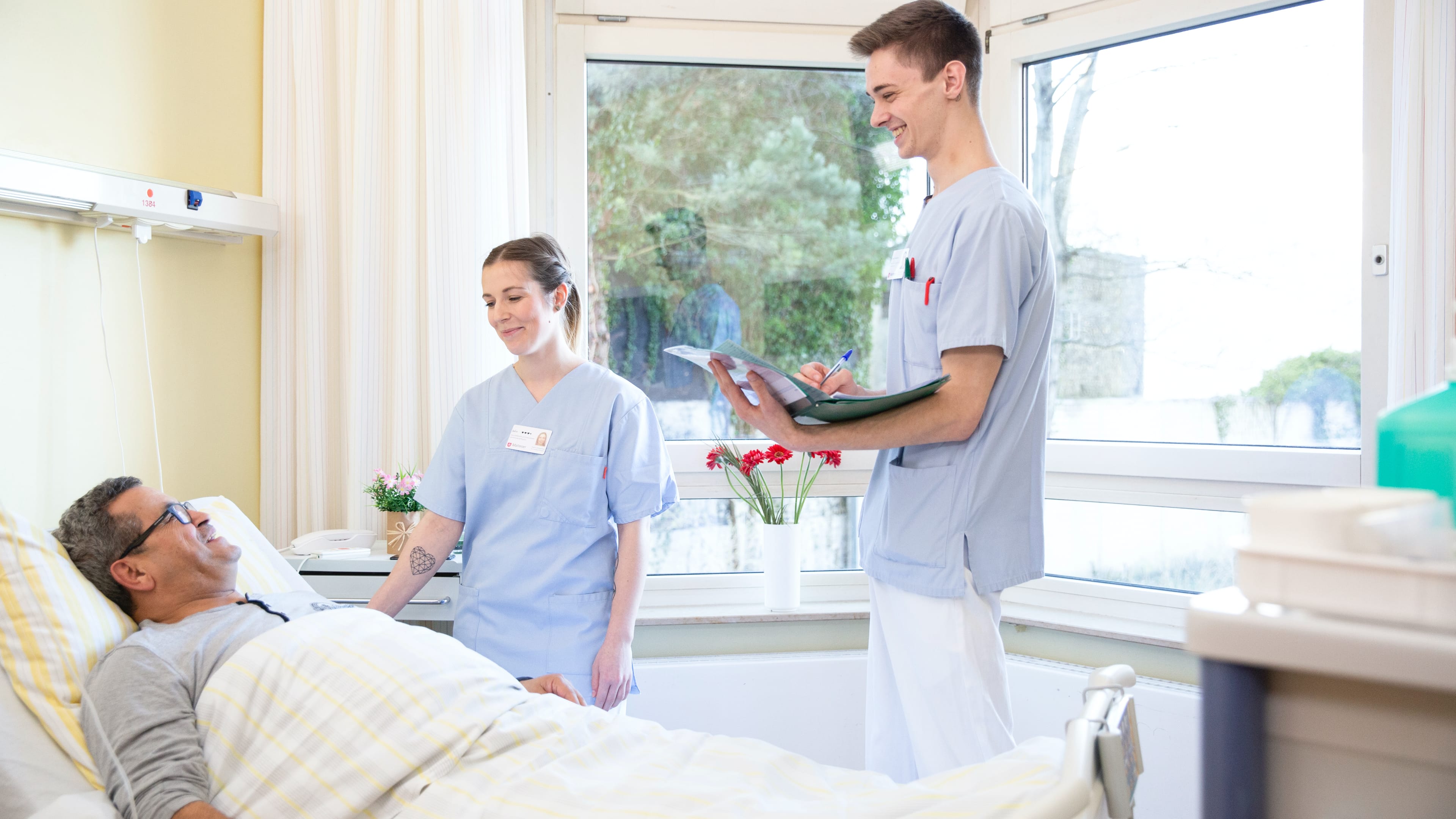 Zwei Pfleger bei der Visite eines Patienten