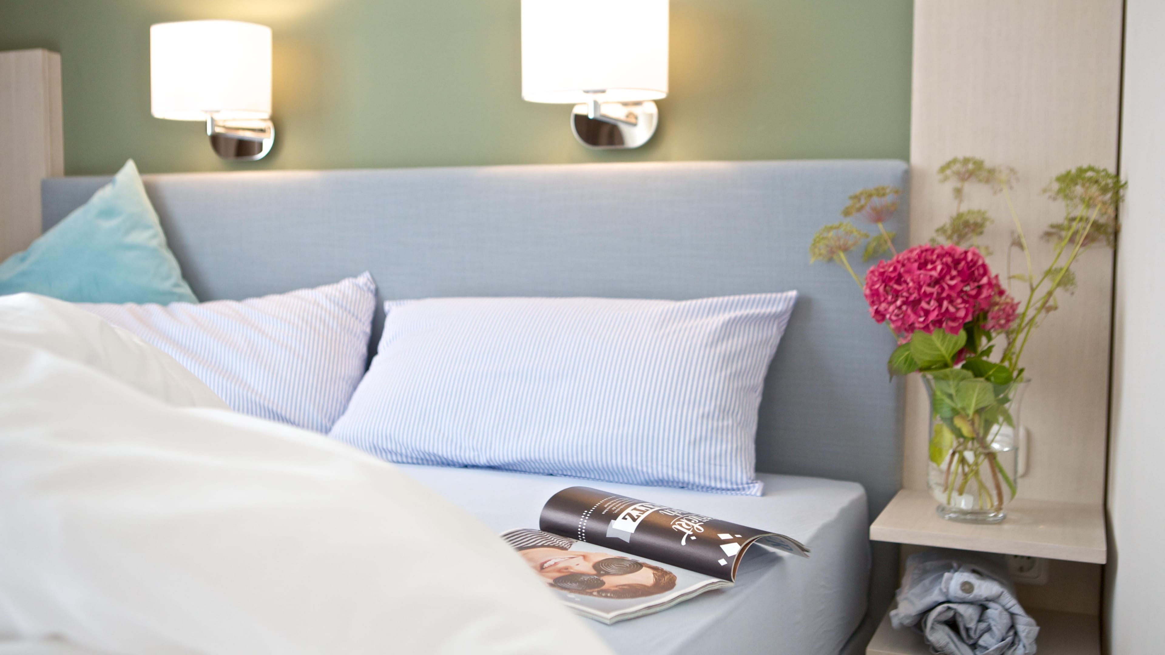 Pinke Blumen stehen auf einem Nachttisch