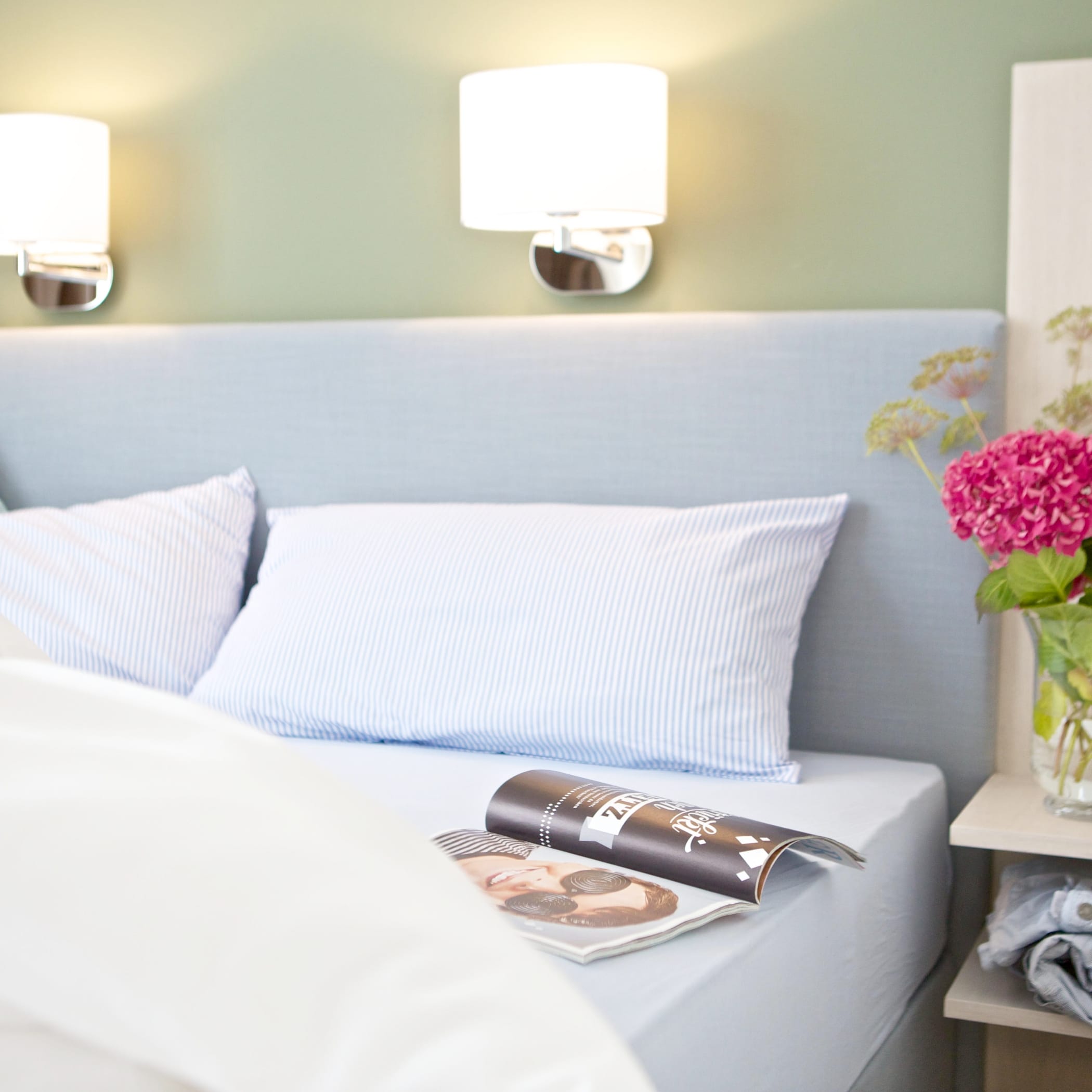 hochzwei_jess_teaser_04.jpg Ein aufgeklapptes Magazin liegt auf einem frisch bezogenem Hotelbett