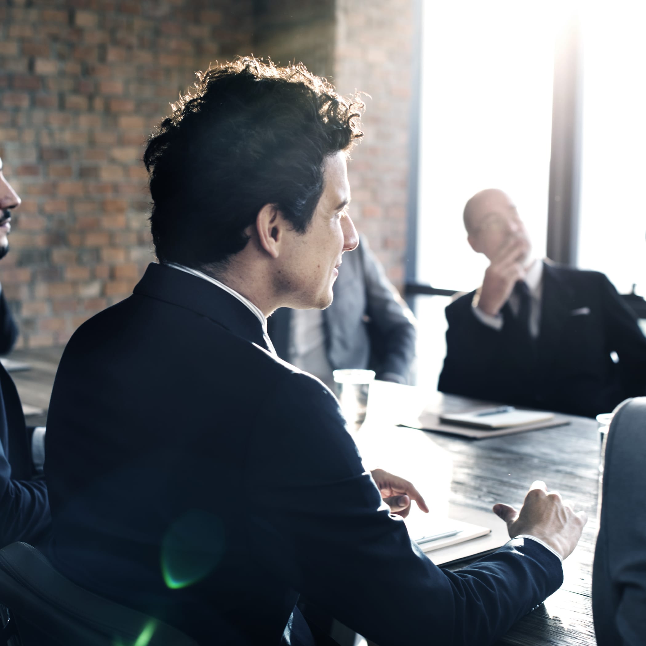 hochzwei_meche_teaser_06.jpg Mann im schwarzen Anzug sitzt in einem Meeting