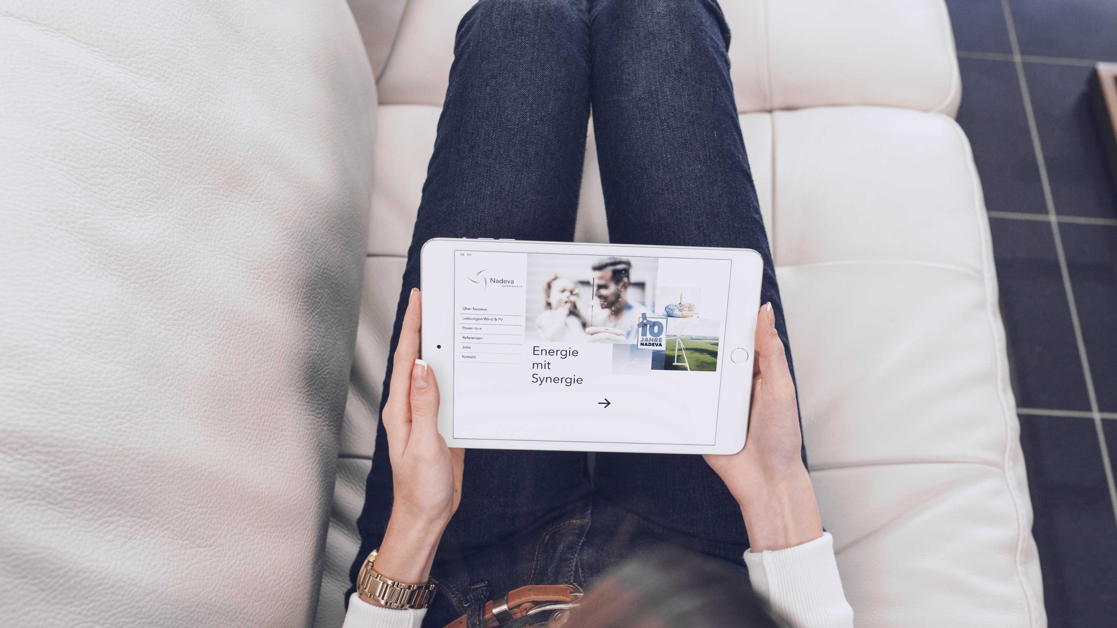 Frau sitzt mit Ipad auf einem hellen Sofa