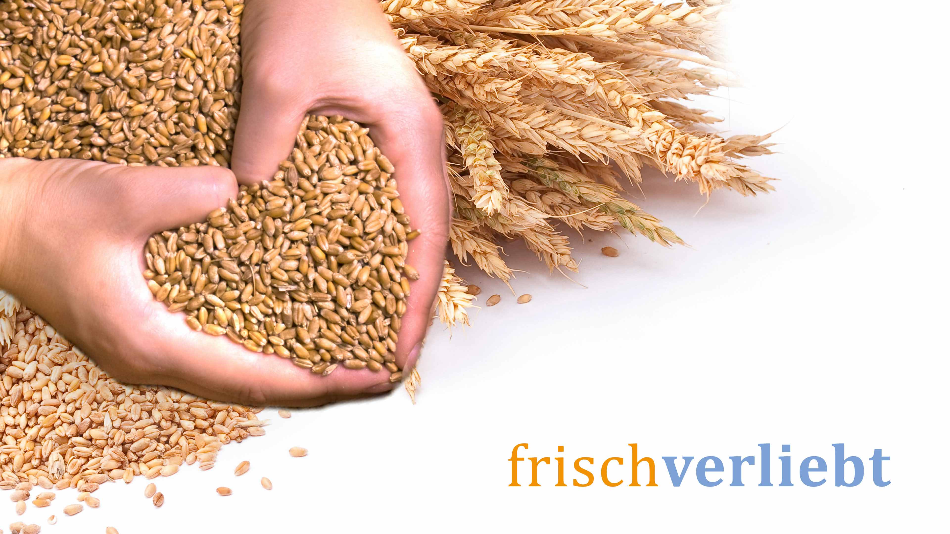 Person macht mit der Hand ein Herz aus Getreide