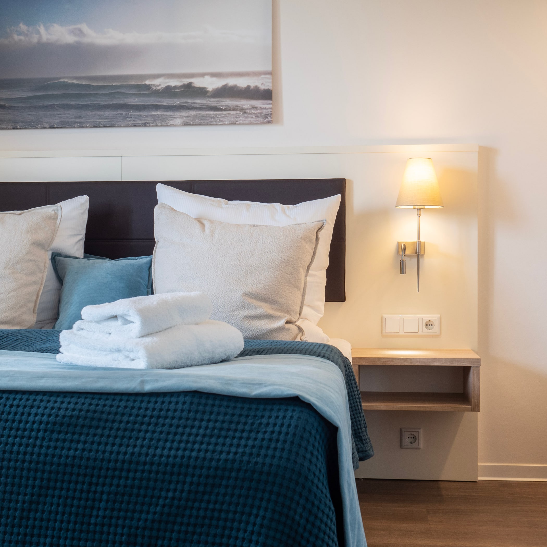 hochzwei_ofv_teaser_04.jpg Blick auf ein Bett in einem Hotelzimmer mit blauer Bettwäsche