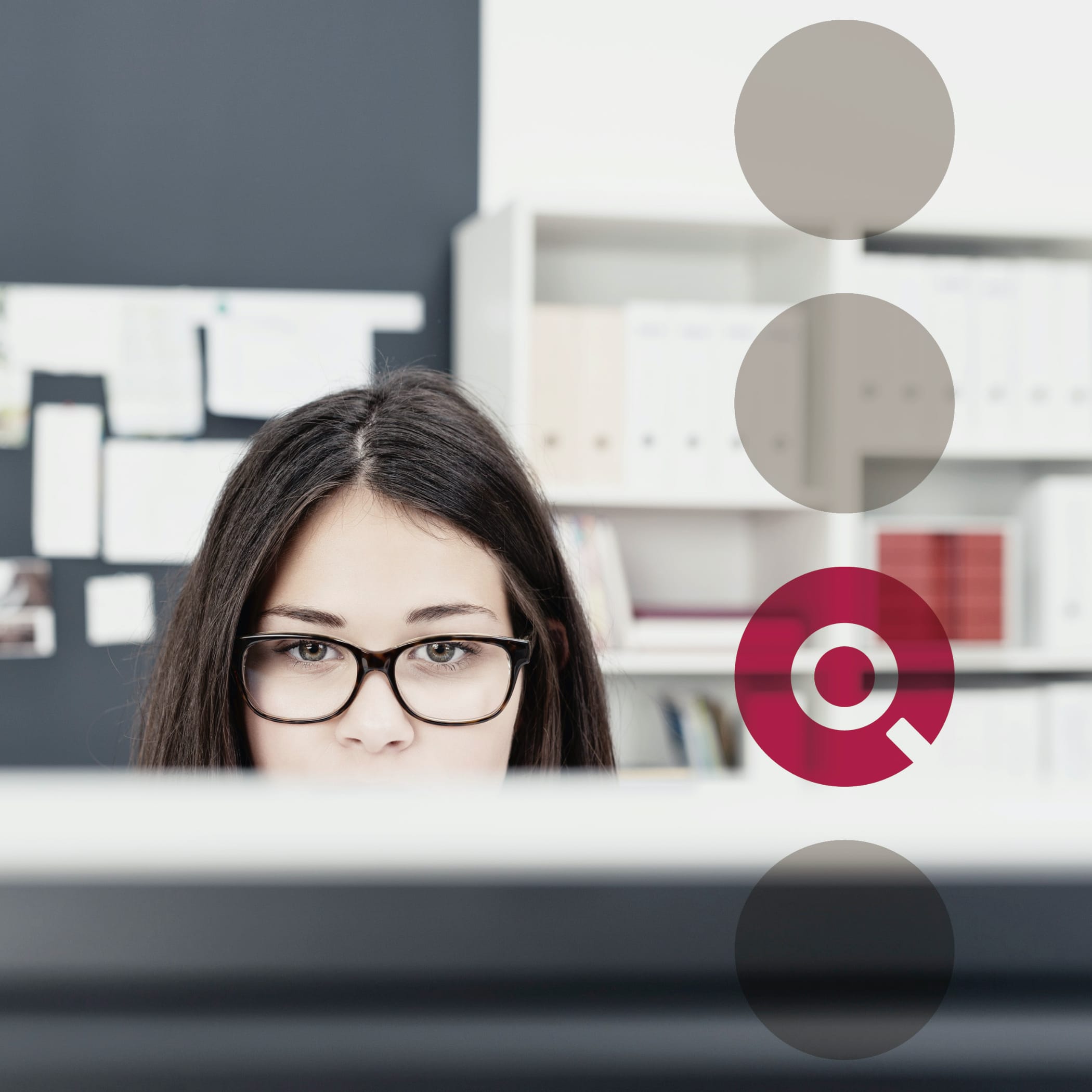 Blick über den Computer auf den Schreibtisch einer Frau