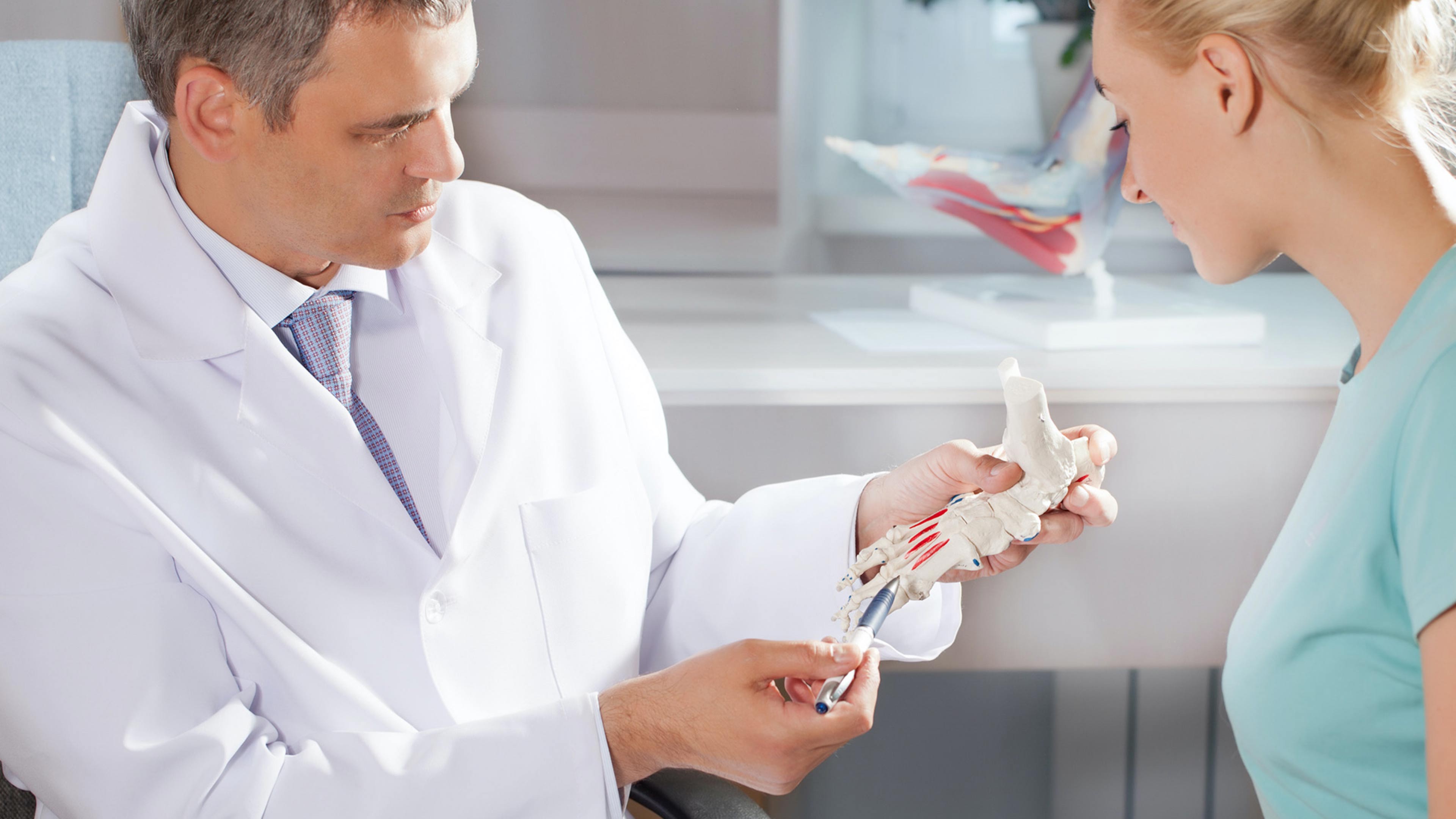 hochzwei_sana_slider_02.jpg Arzt zeigt Patientin etwas am Knochen