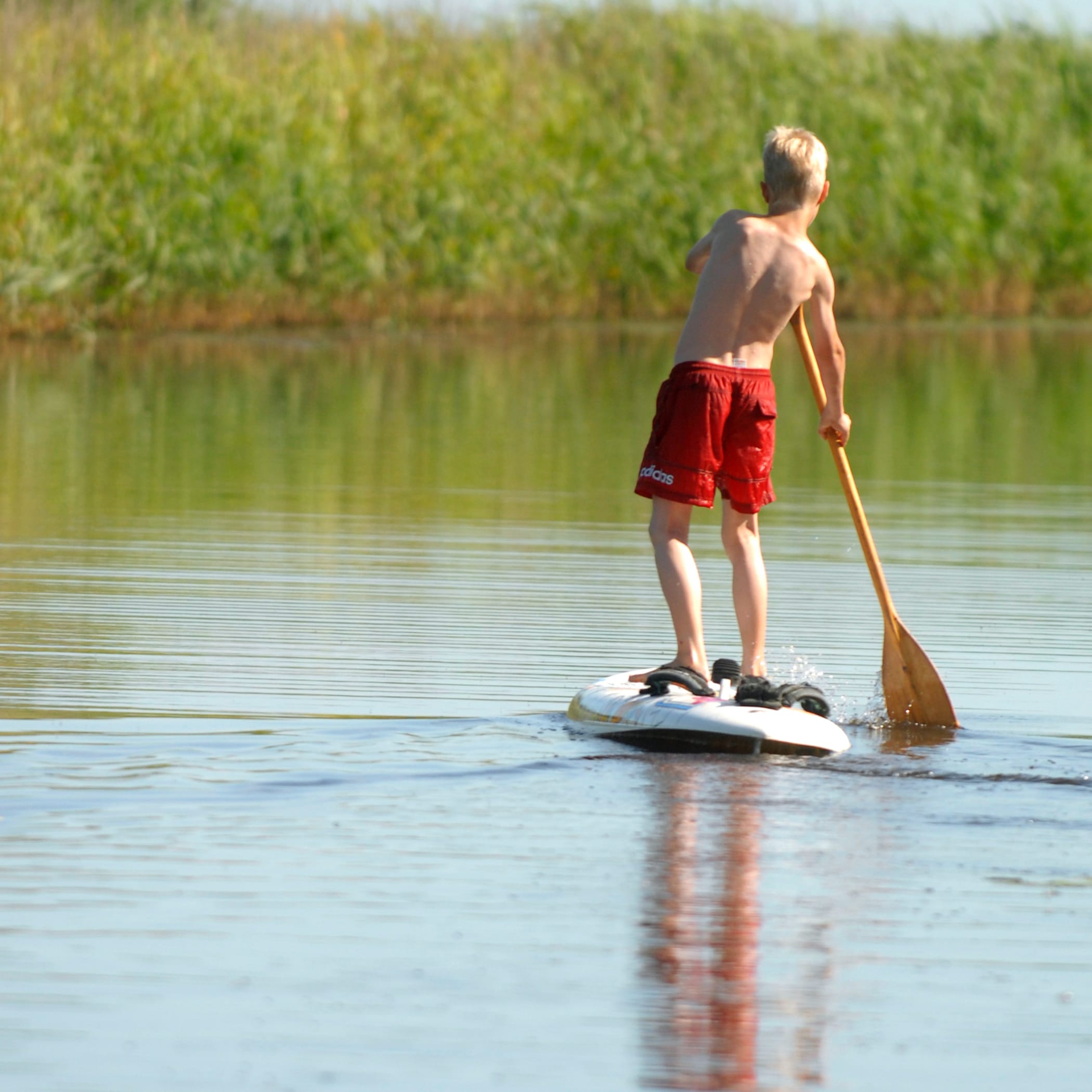Ein Kind in roter Hose steht auf einem Sub