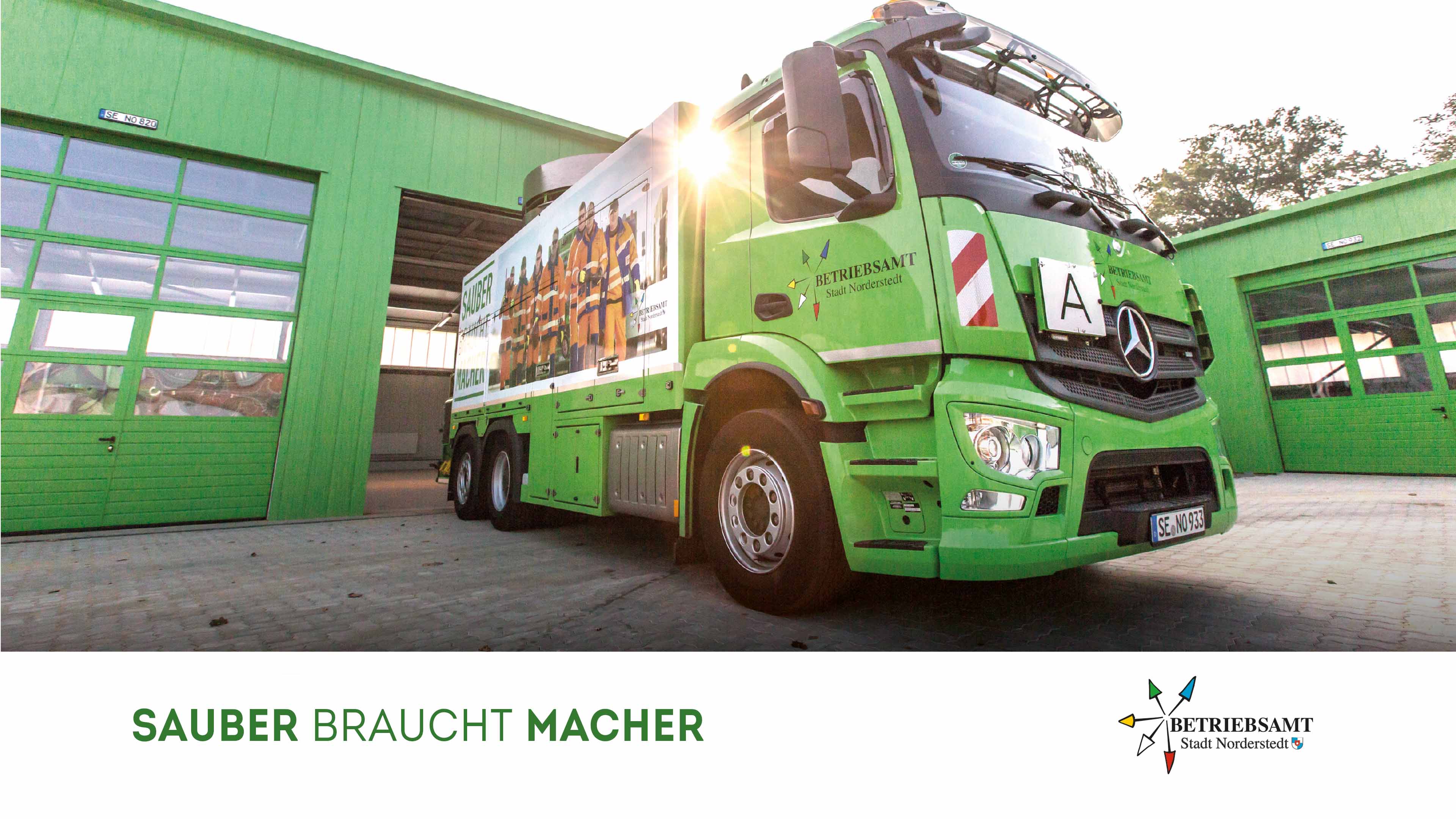 Grüner Müllwagen steht vor einer grünen Halle