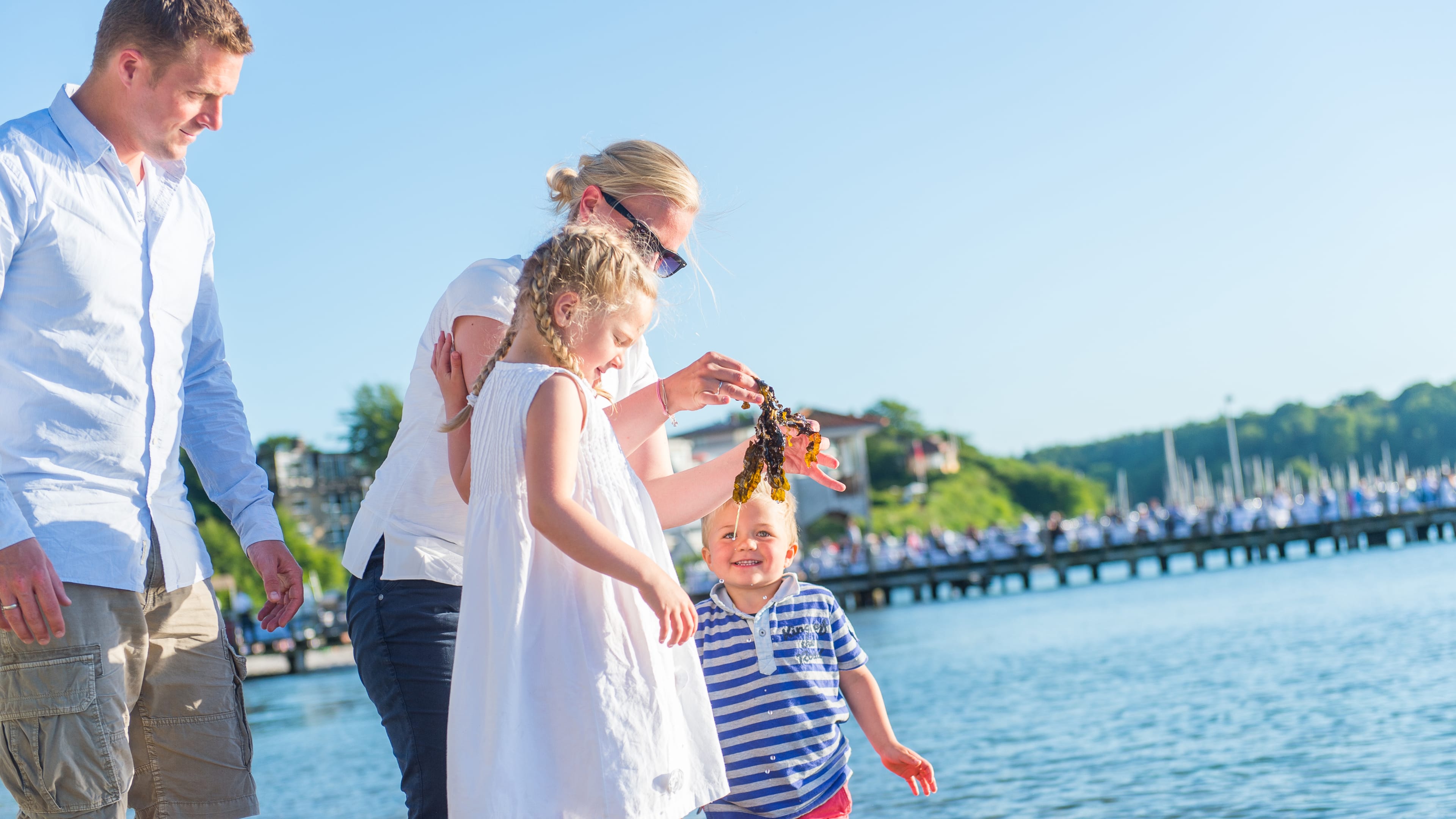 Mutter und Vater spielen mit Kindern am Strand