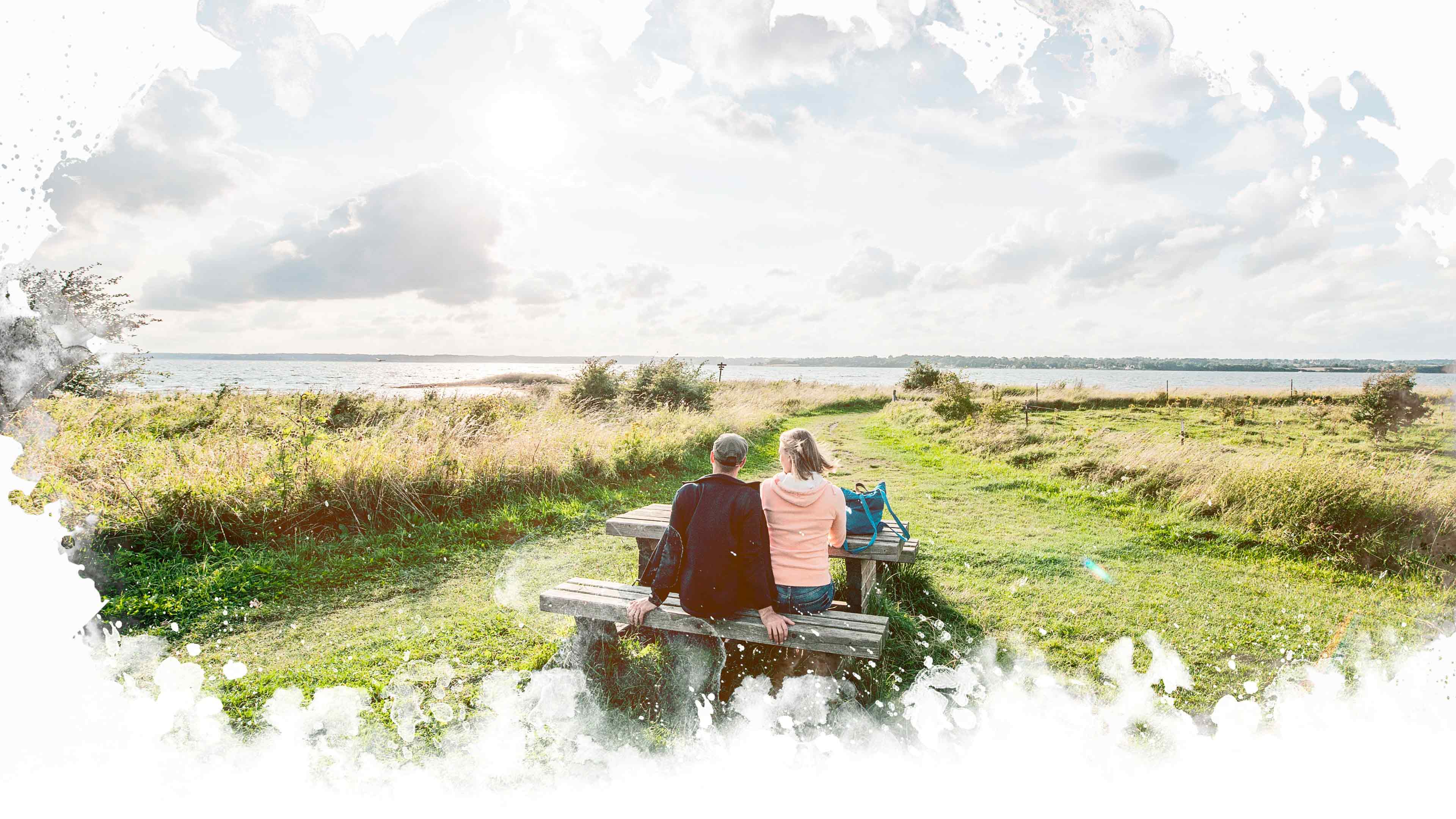 hochzwei_taff2_slider_02.jpg Pärchen sitzt auf einer Holzbank am Wasser