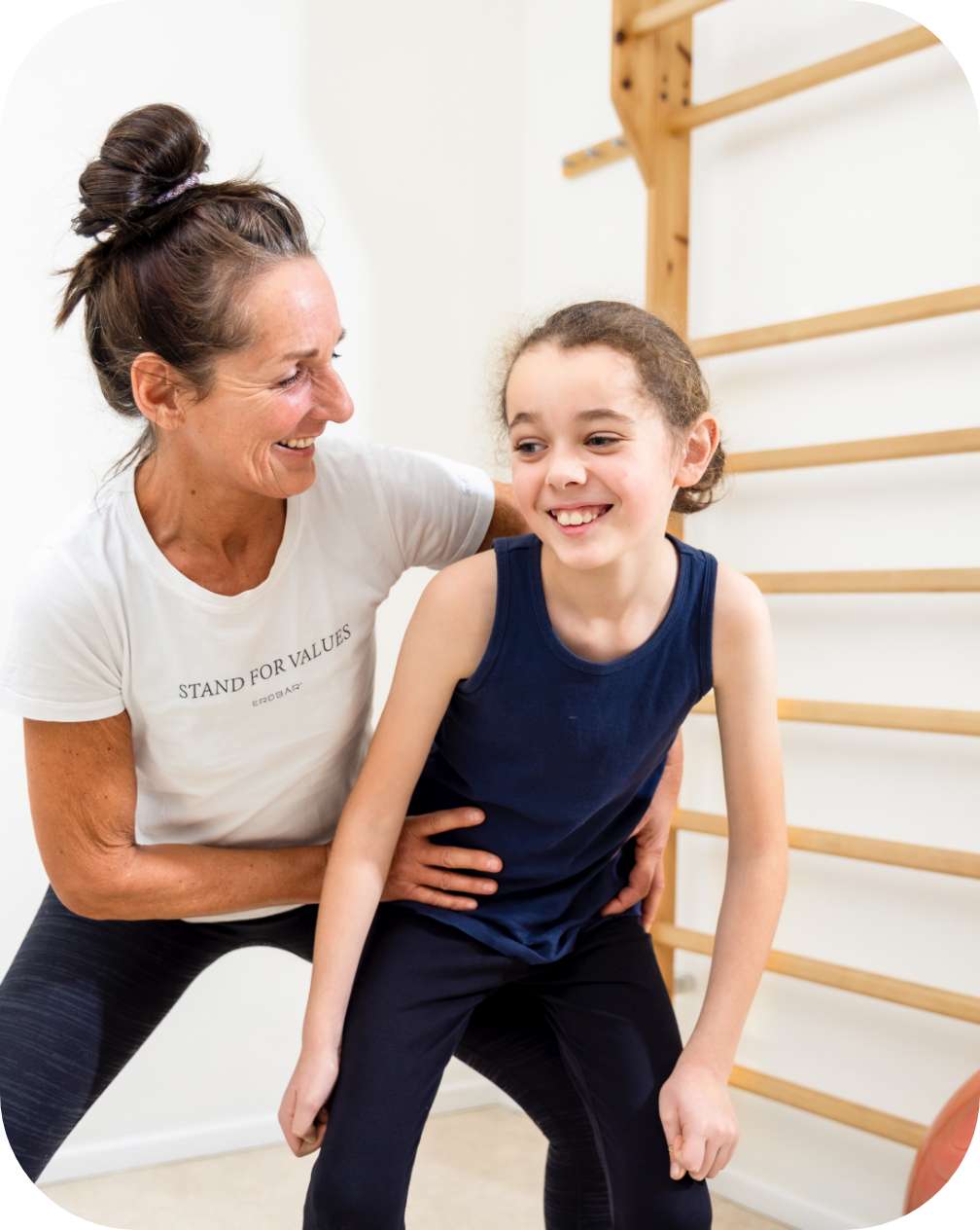 Zu sehen ist eine Therapeutin, die mit einem Kind in einem Behandlungsraum eine Übung durchführt.