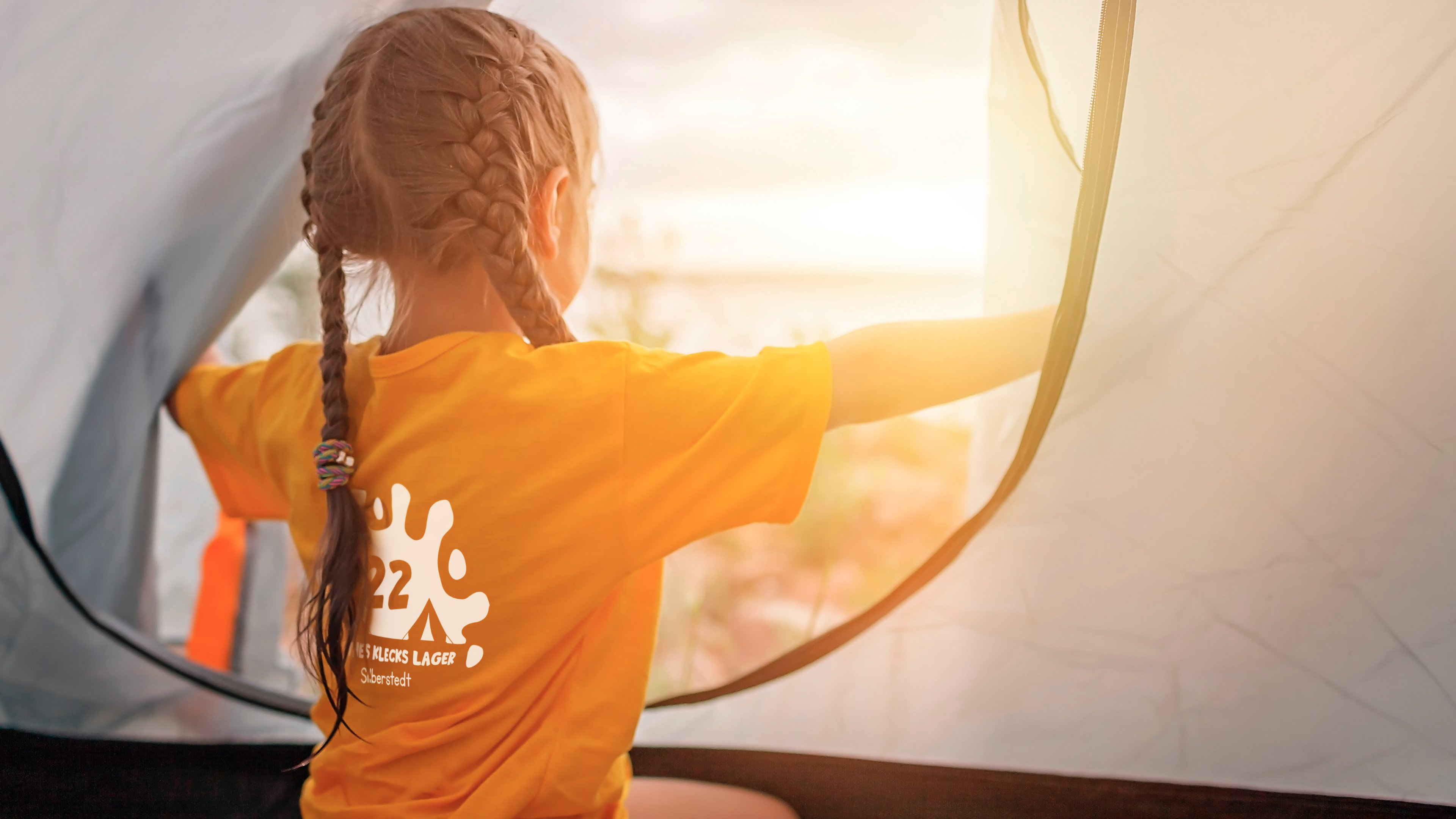 Ein Kind mit Zöpfen öffnet ein Zelt