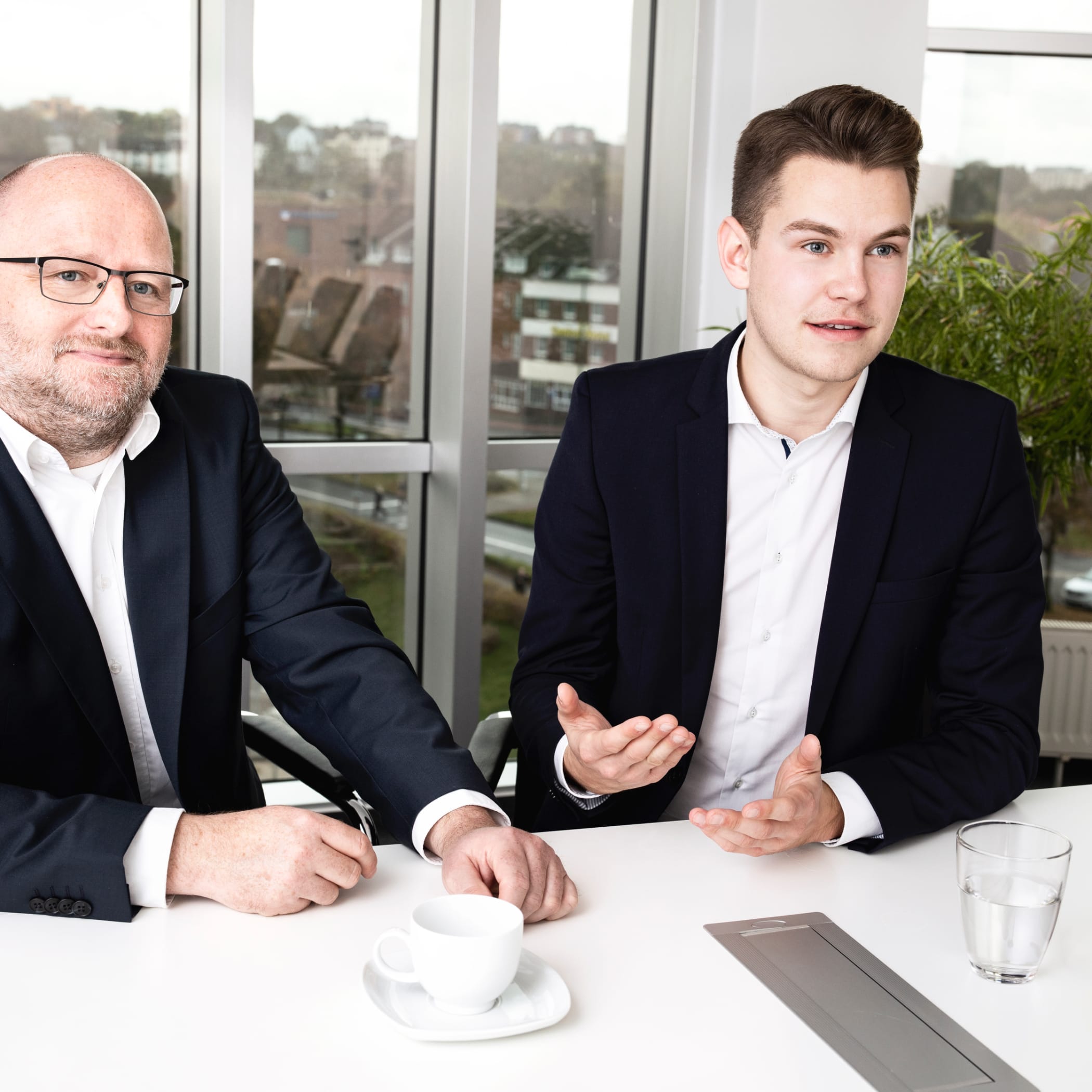 hochzwei_ttp_teaser_01.jpg Zwei Männer im Anzug sitzen im Meeting bei ttp