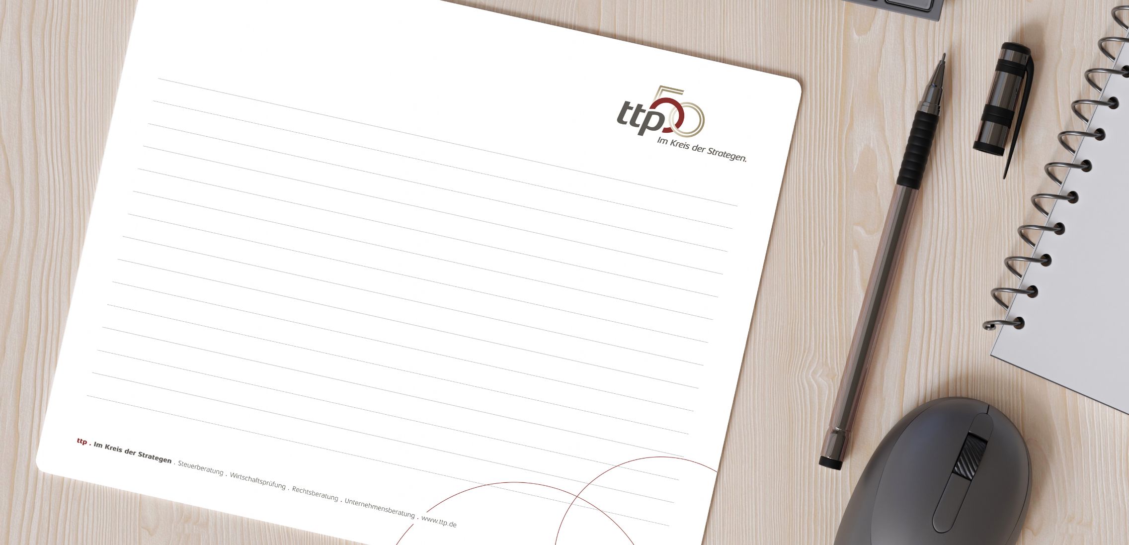 Ein Notizblock mit dem Jubiläumslogo auf einem Schreibtisch