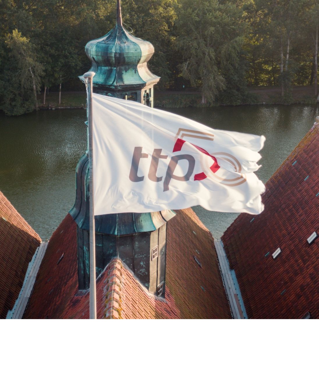 Eine Flagge auf dem Dach des Schloss Glücksburg mit dem ttp Jubiläumslogo