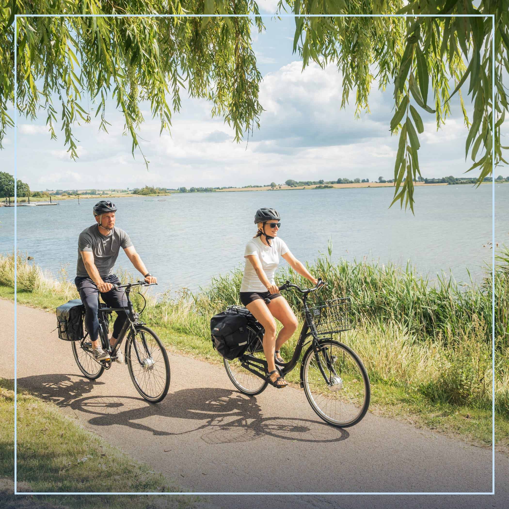 hochzwei_kvideAdvertorial_teaser_11.jpg Zwei Personen fahren Fahrrad am Wasser