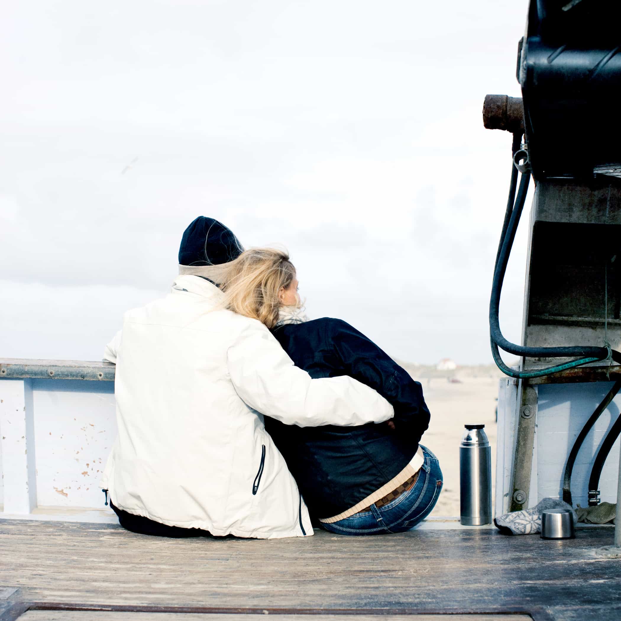 hochzwei_vide_teaser_04.jpg Pärchen sitzt Arm in Arm an einem Steg