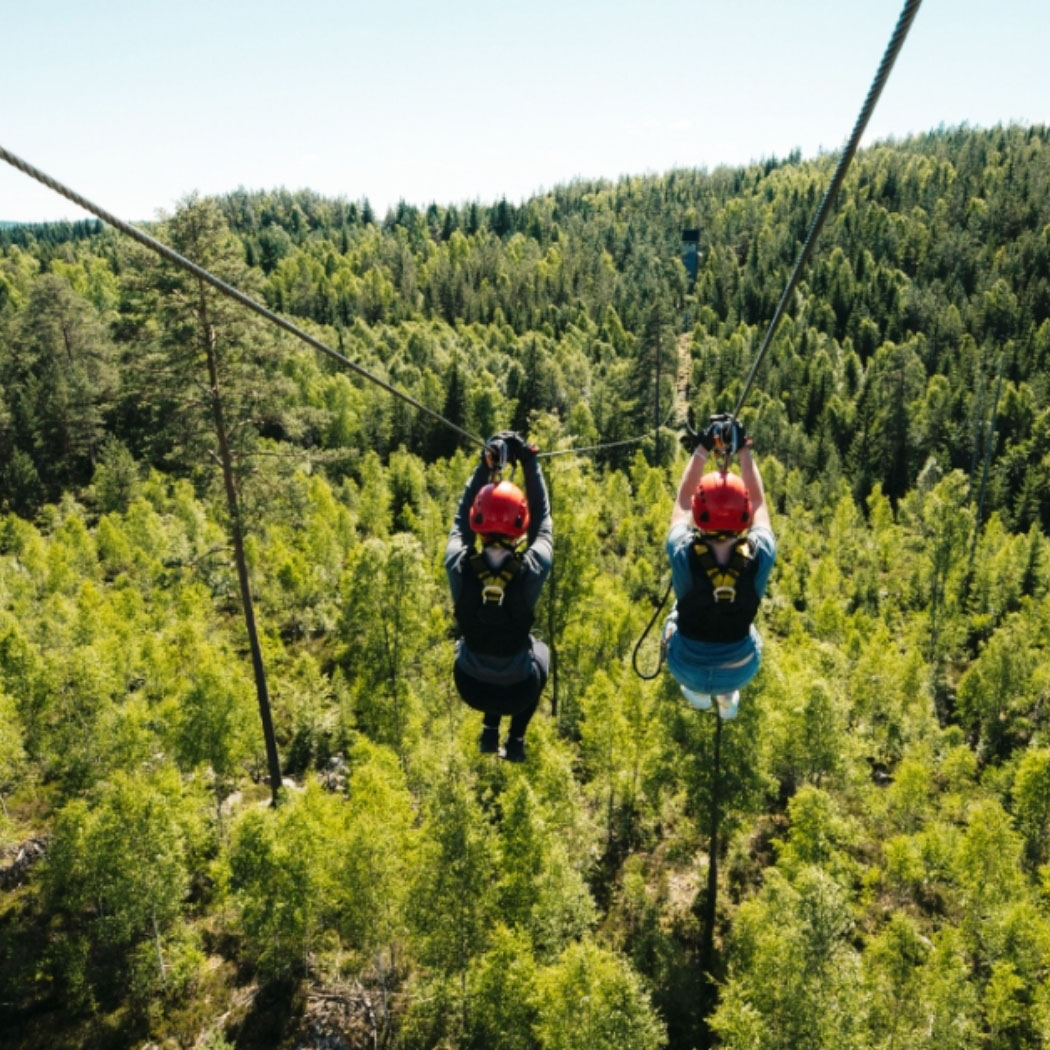 Zwei Frauen fahren Seilbahn über einen Wald