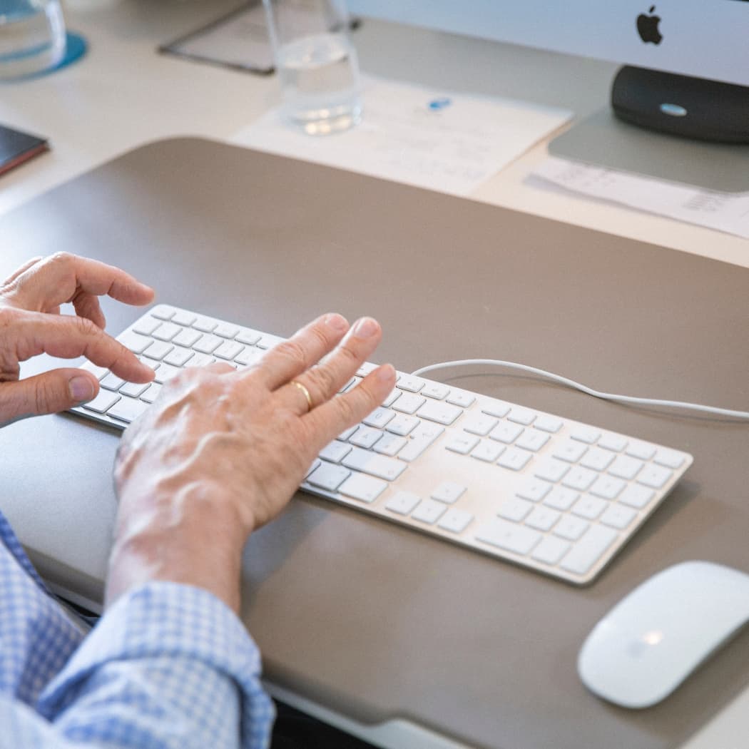 hochzwei_agenur_teaser_05.jpg Mitarbeiter tippt auf weißer Tastatur