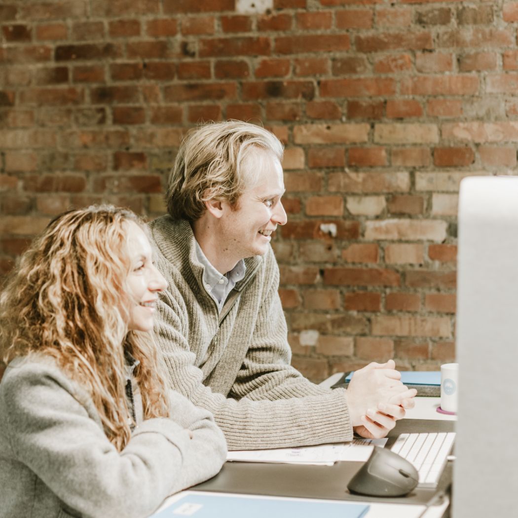 Zwei Mitarbeiter von Hochzwei gemeinsam an einem PC-Platz