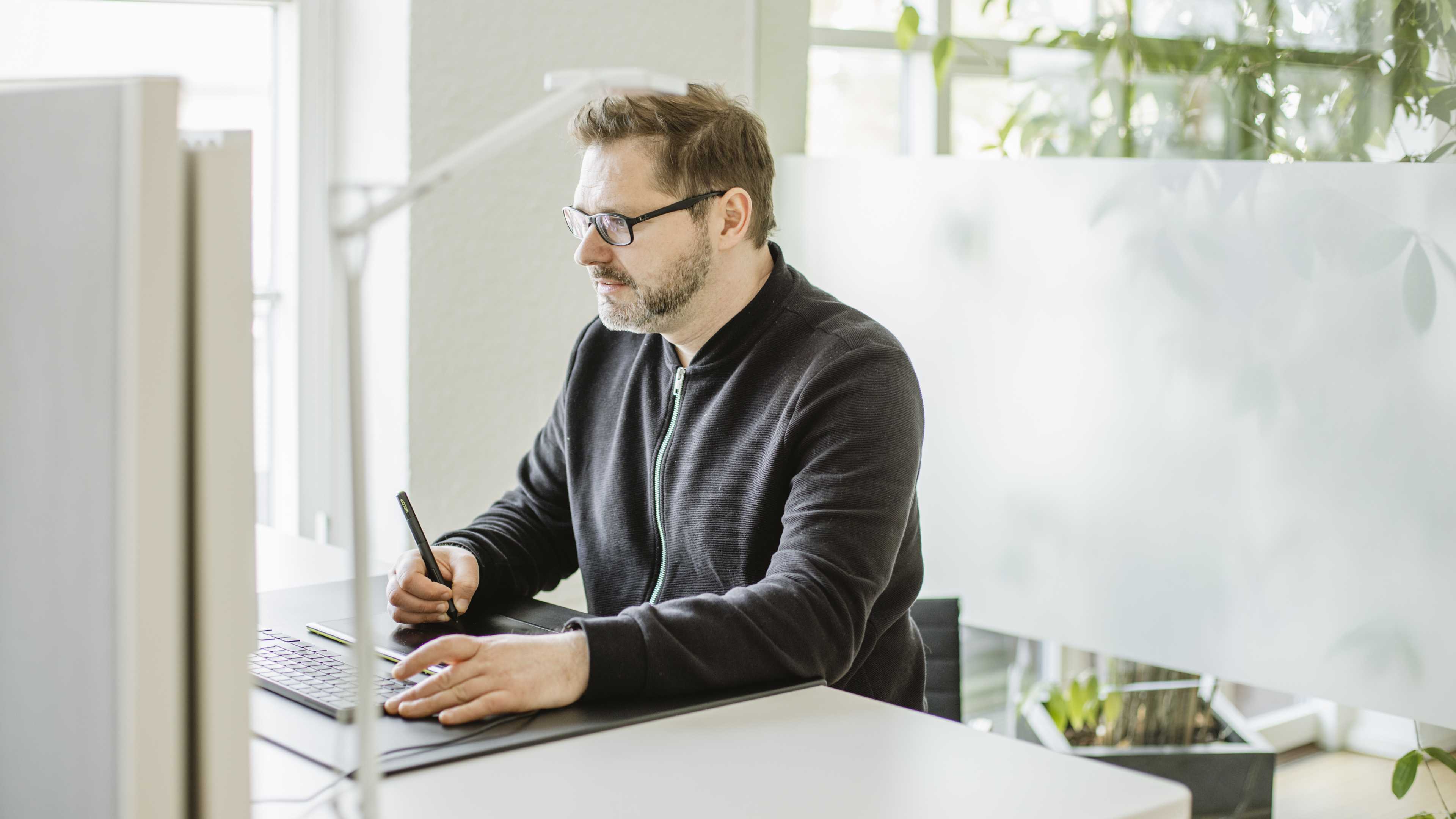 Ein Mitarbeiter von Hochzwei an seinem Schreibtisch mit seinem Zeichenpad
