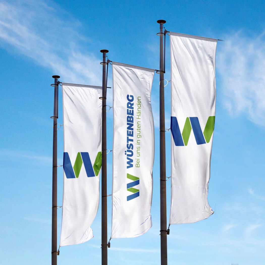 Drei weiße Fahnen der  Firma Wüstenberg mit Logo und Design in blau und grün