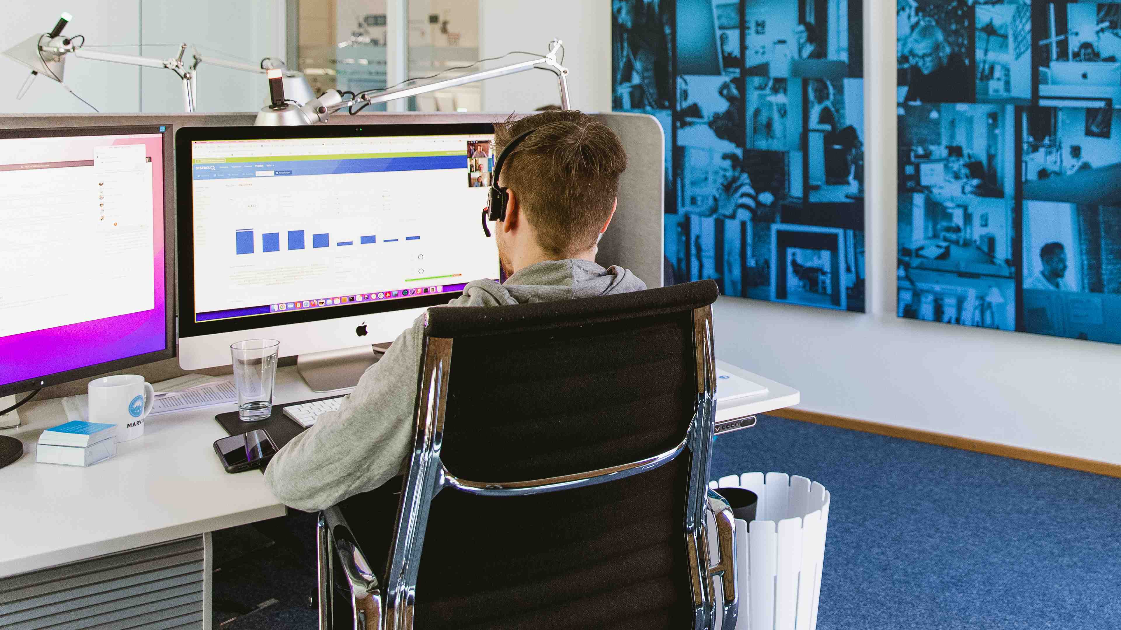 Ein Kollege von Hochzwei an seinem Arbeitsplatz von hinten fotografiert. Er ist gerade in einem Meeting und schaut sich eine Auswertung an.