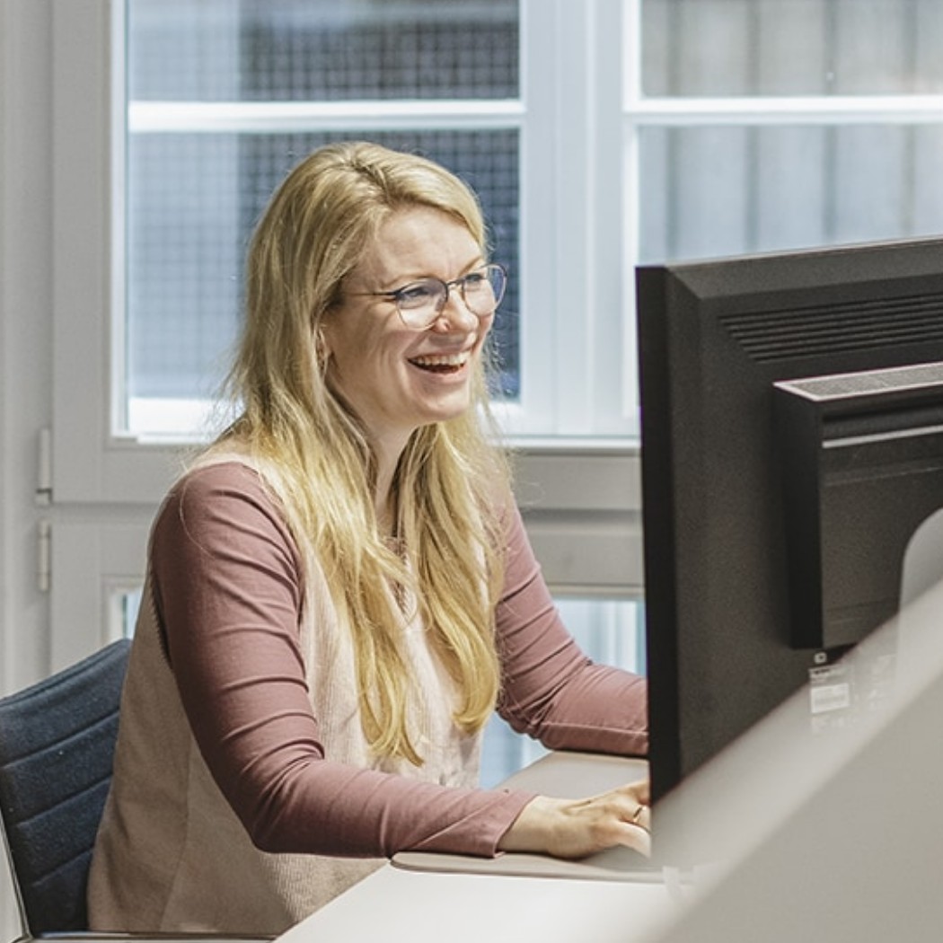 Eine Mitarbeiterin von Hochzwei lächelnd an ihrem Arbeitsplatz