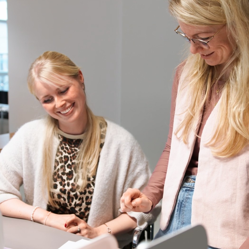 Zwei Kolleginnen von Hochzwei schauen sich gemeinsam etwas an