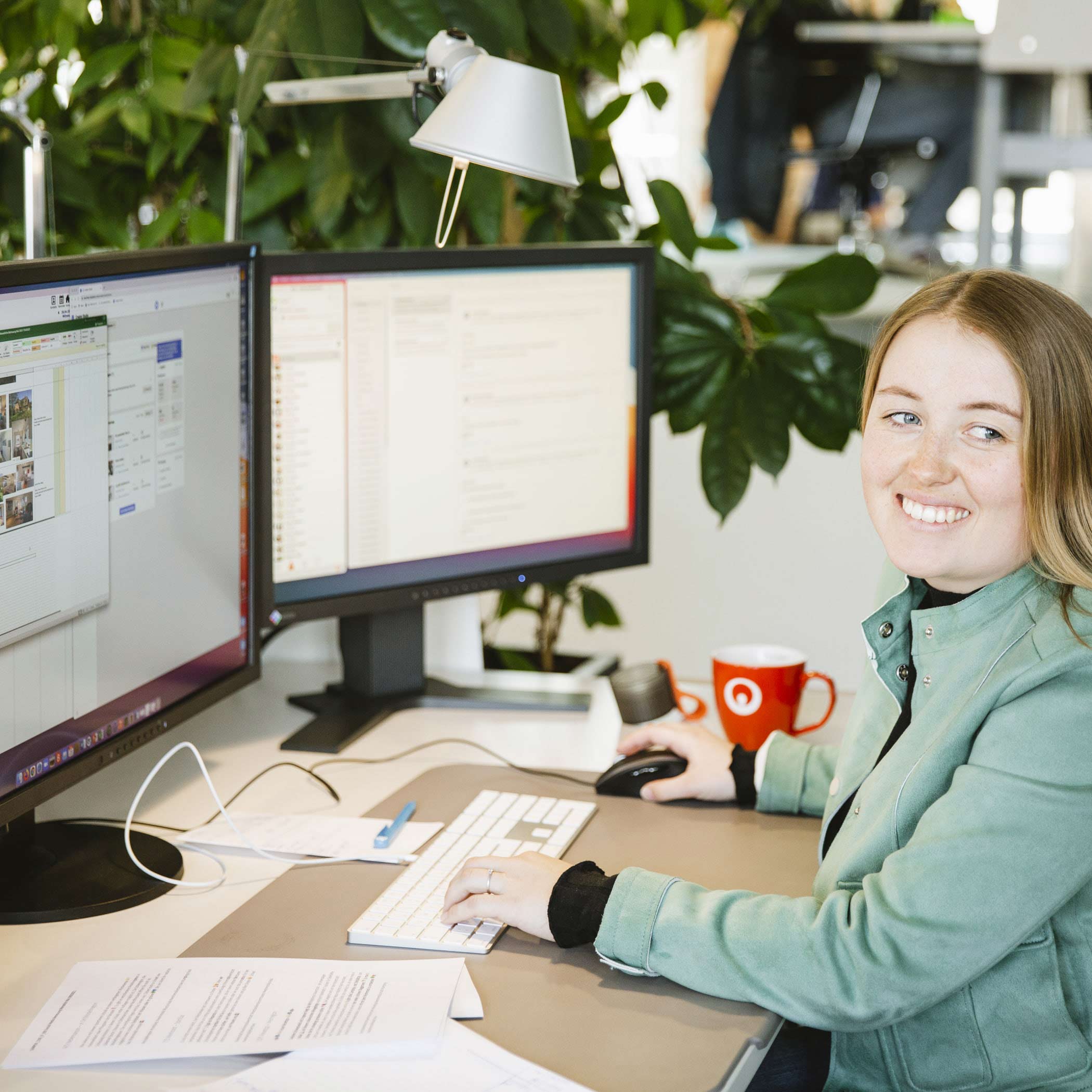Lächelnde Mitarbeiterin sitzt am Schreibtisch