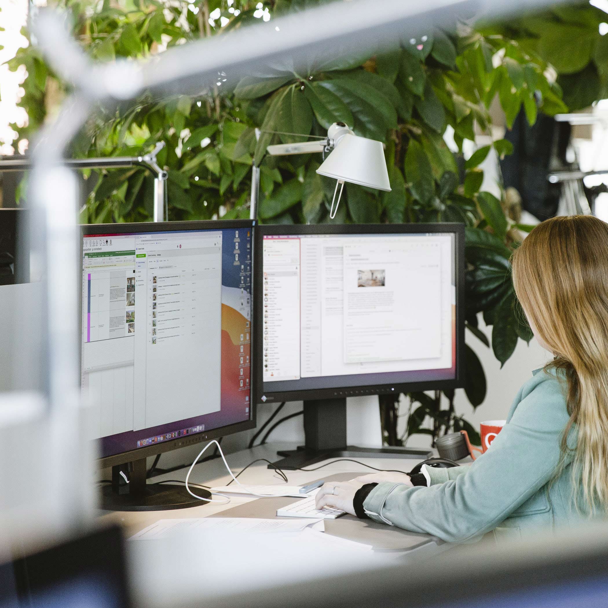 Mitarbeiterin sitzt vor zwei geöffneten Computerbildschirmen