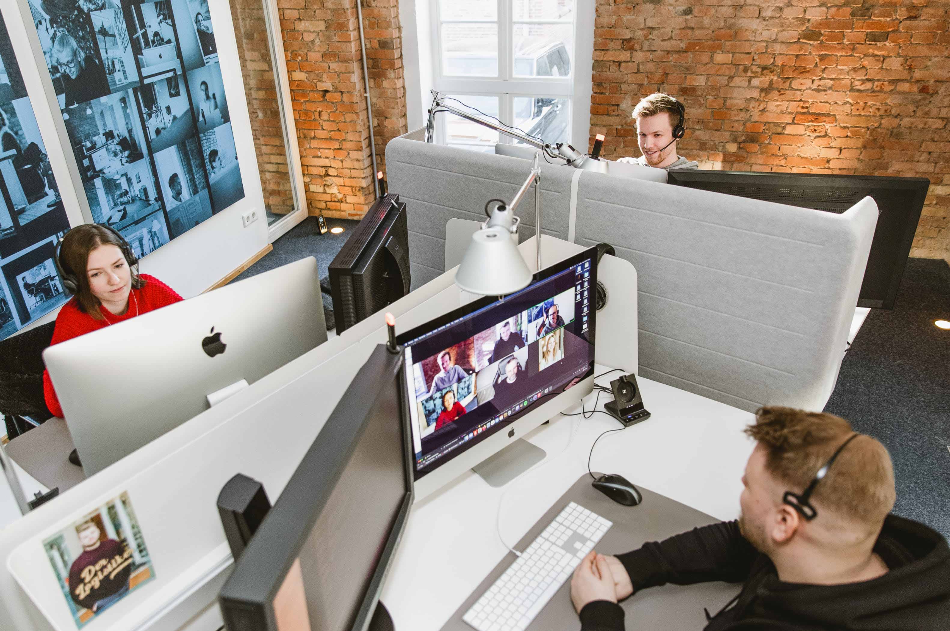 Drei Personen sitzen am Büroschreibtisch