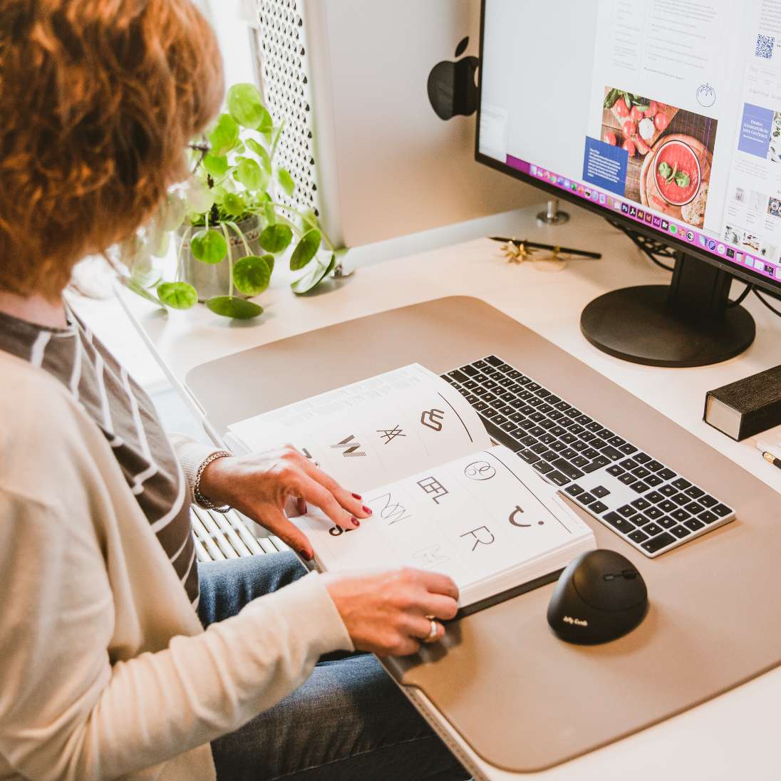 h2_einblicke_50Jahre_teaser_02.jpg Steffi blättert in einem Buch mit unterschiedlichen Logos.