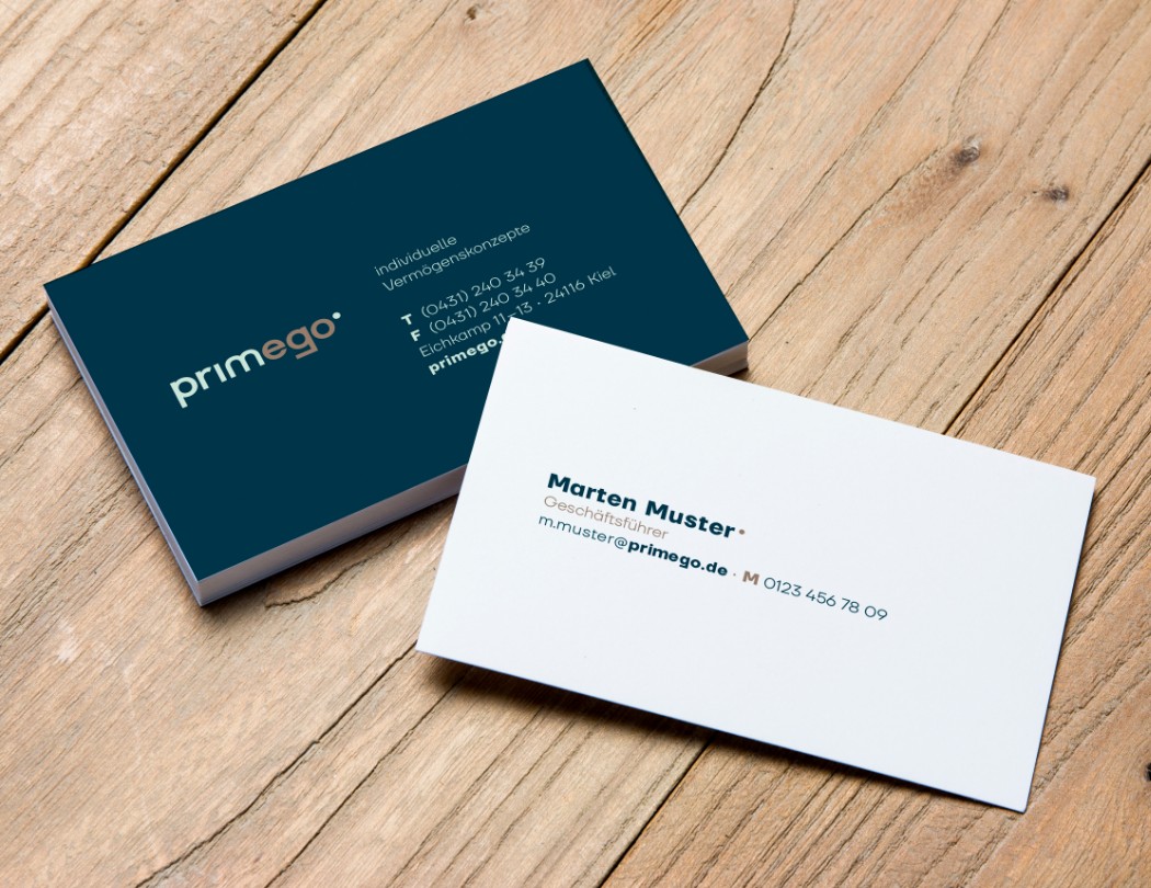 h2_einblicke_namensfindung_teaser_07.jpg Mustervisitenkarten von primego auf einem Holztisch.